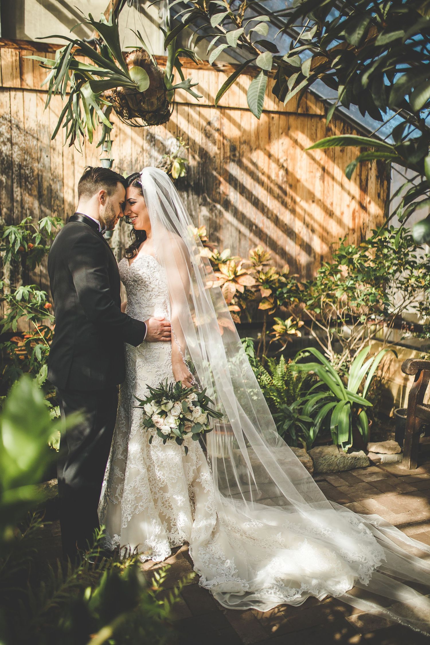 A wedding couple shares an intimate moment in a sunlit garden setting.
