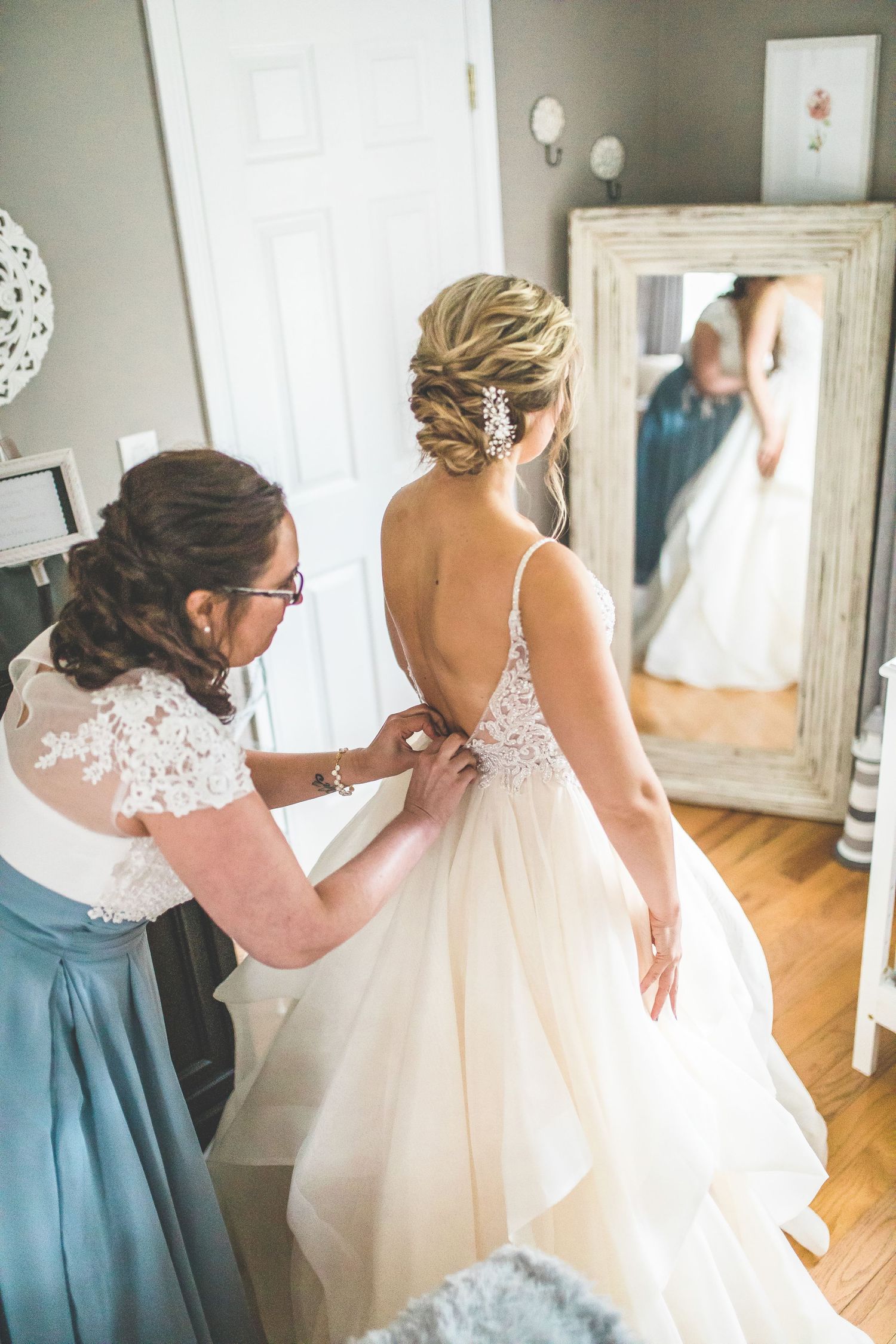 Wedding dress preparation scene with attendants helping with final adjustments.
