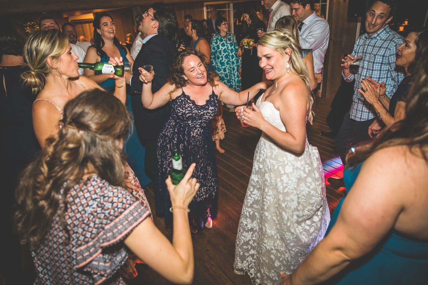 Energetic crowd dancing and celebrating at a nighttime wedding reception.