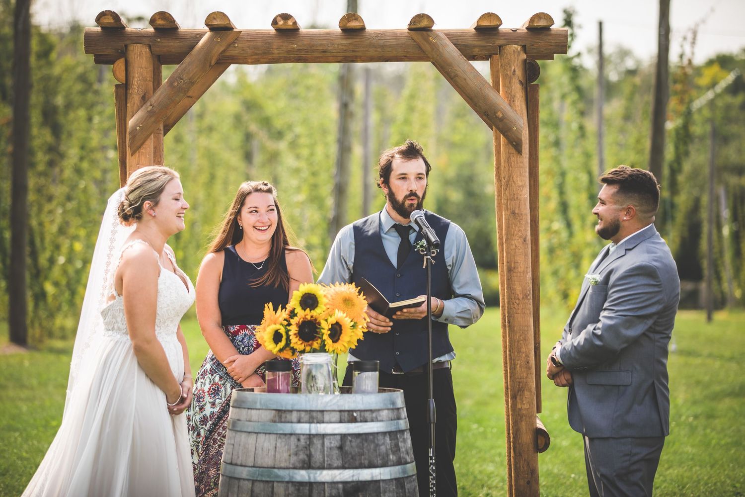 Wedding ceremony setup with wooden barrels and rustic decor in a scenic field.