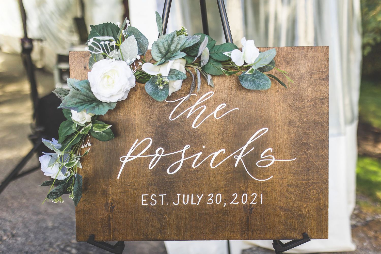 Rustic wooden wedding signs and decor with white floral arrangements and greenery.