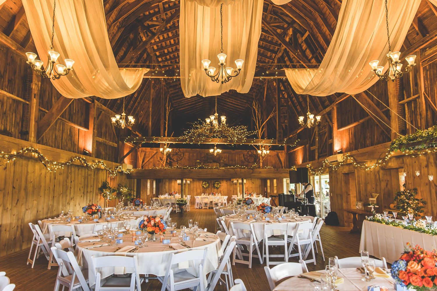 Rustic barn wedding venue with draped fabric and string lights creating a romantic atmosphere.