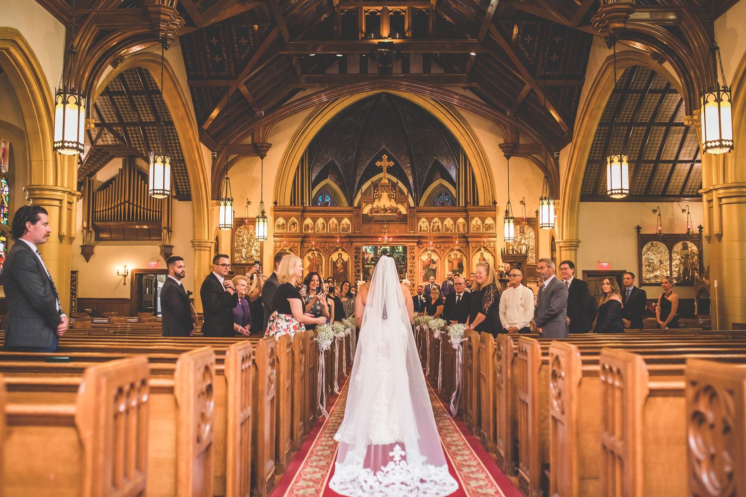 Gothic church interior with wooden beams and stained glass windows during wedding ceremony.