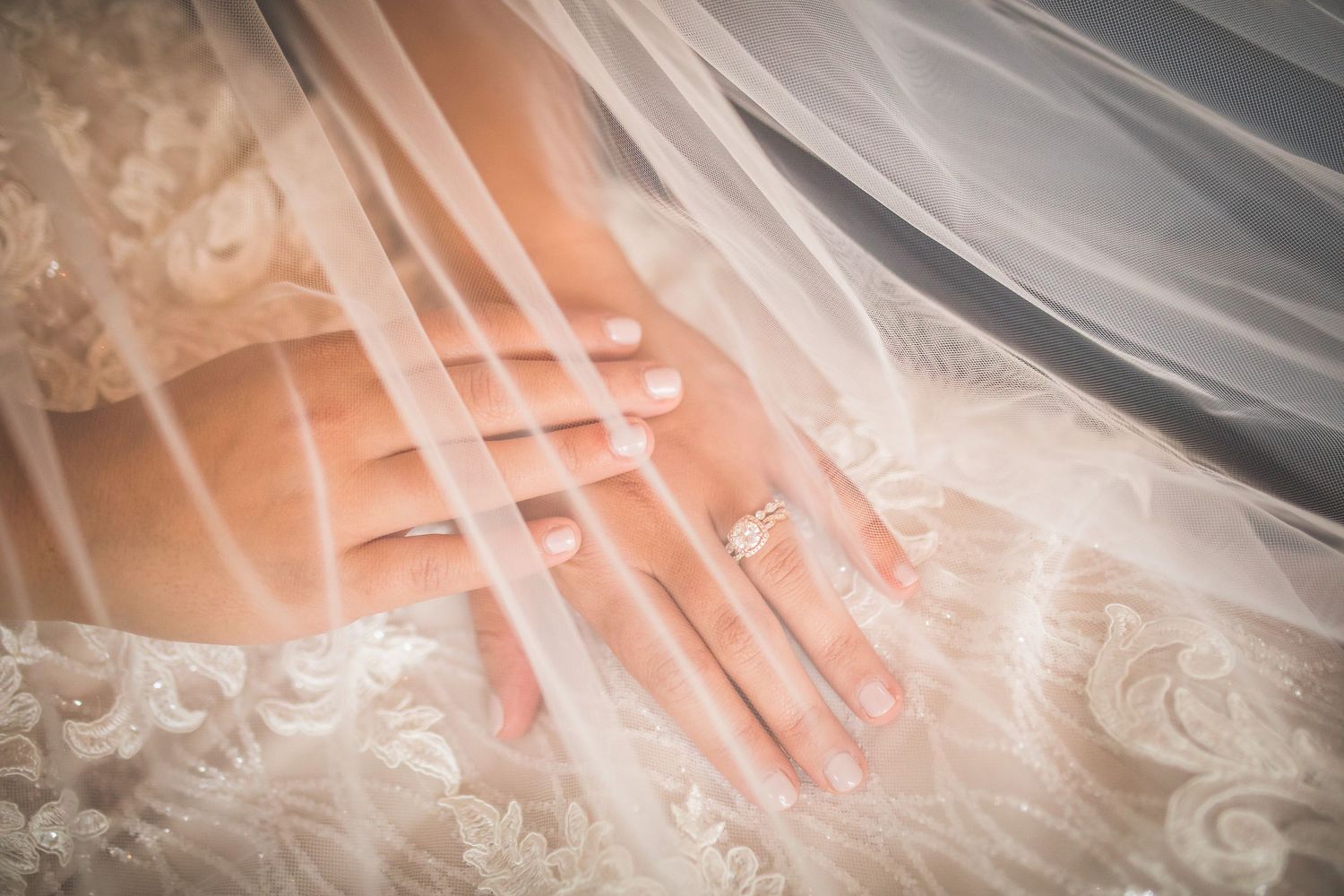Close-up detail of lace wedding dress and veil with delicate embroidery.