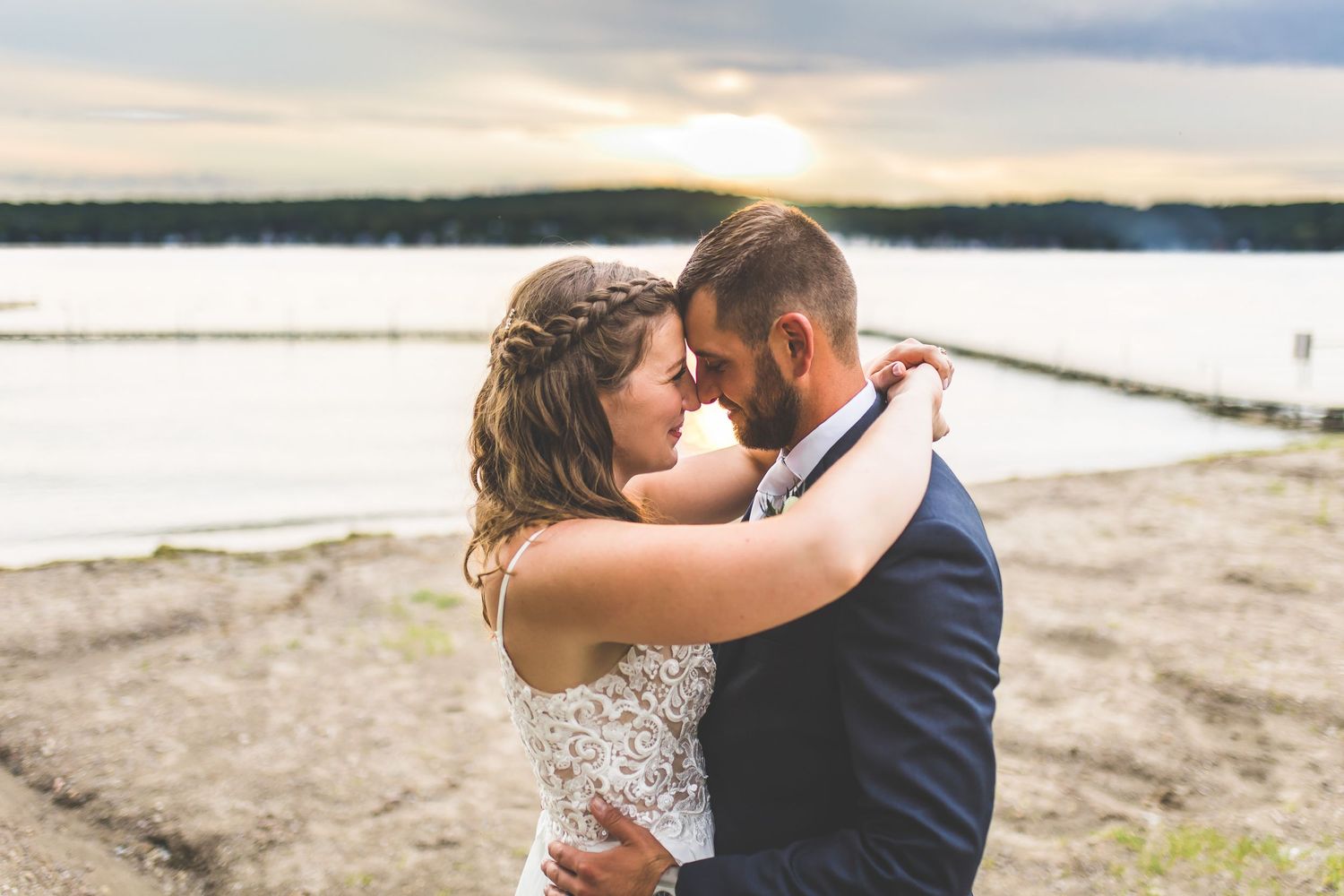 Romantic beach wedding portraits at sunset with water and coastline views.