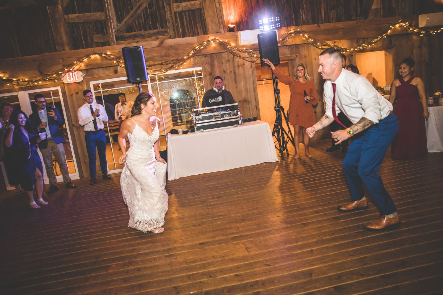 Wedding celebration on a rustic wooden dance floor with string lights overhead.