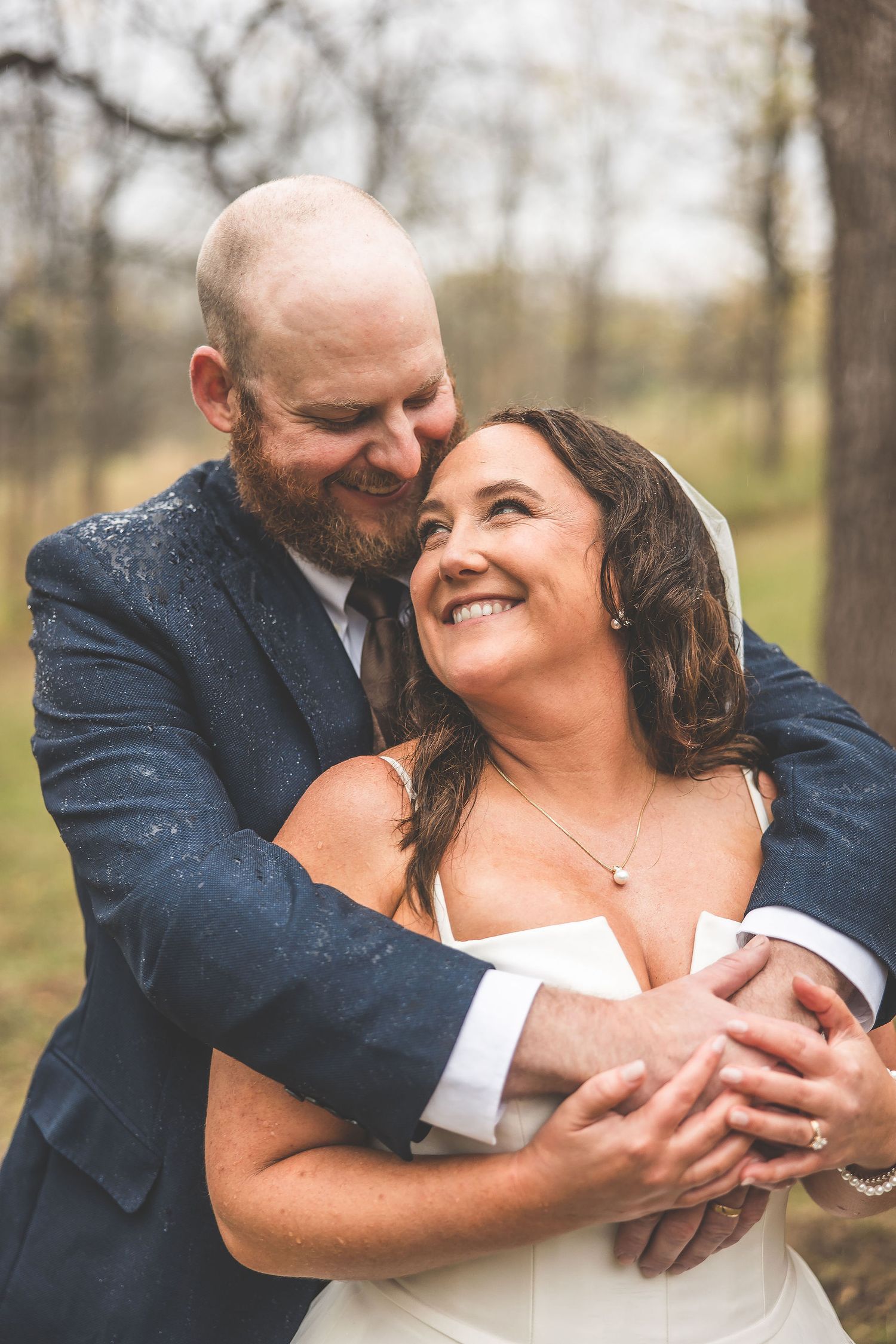 A joyful wedding moment captured as the couple shares laughter in the woods.
