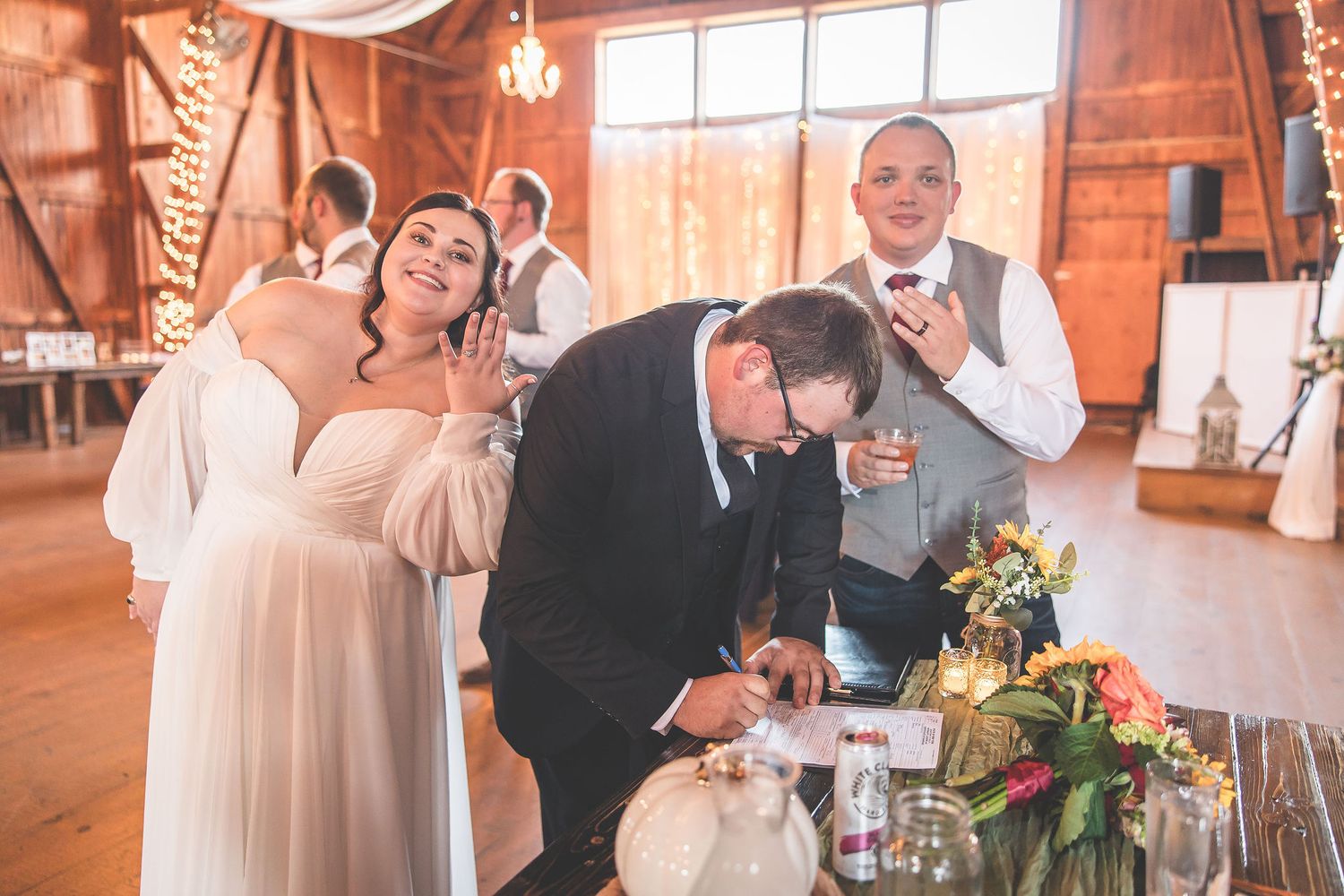 Indoor wedding reception with warm lighting in a rustic barn venue.