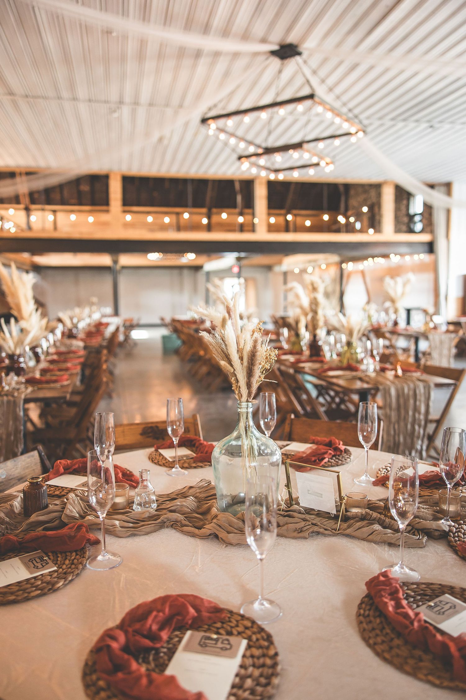 Elegant table settings with white linens, glassware and dried floral centerpieces.
