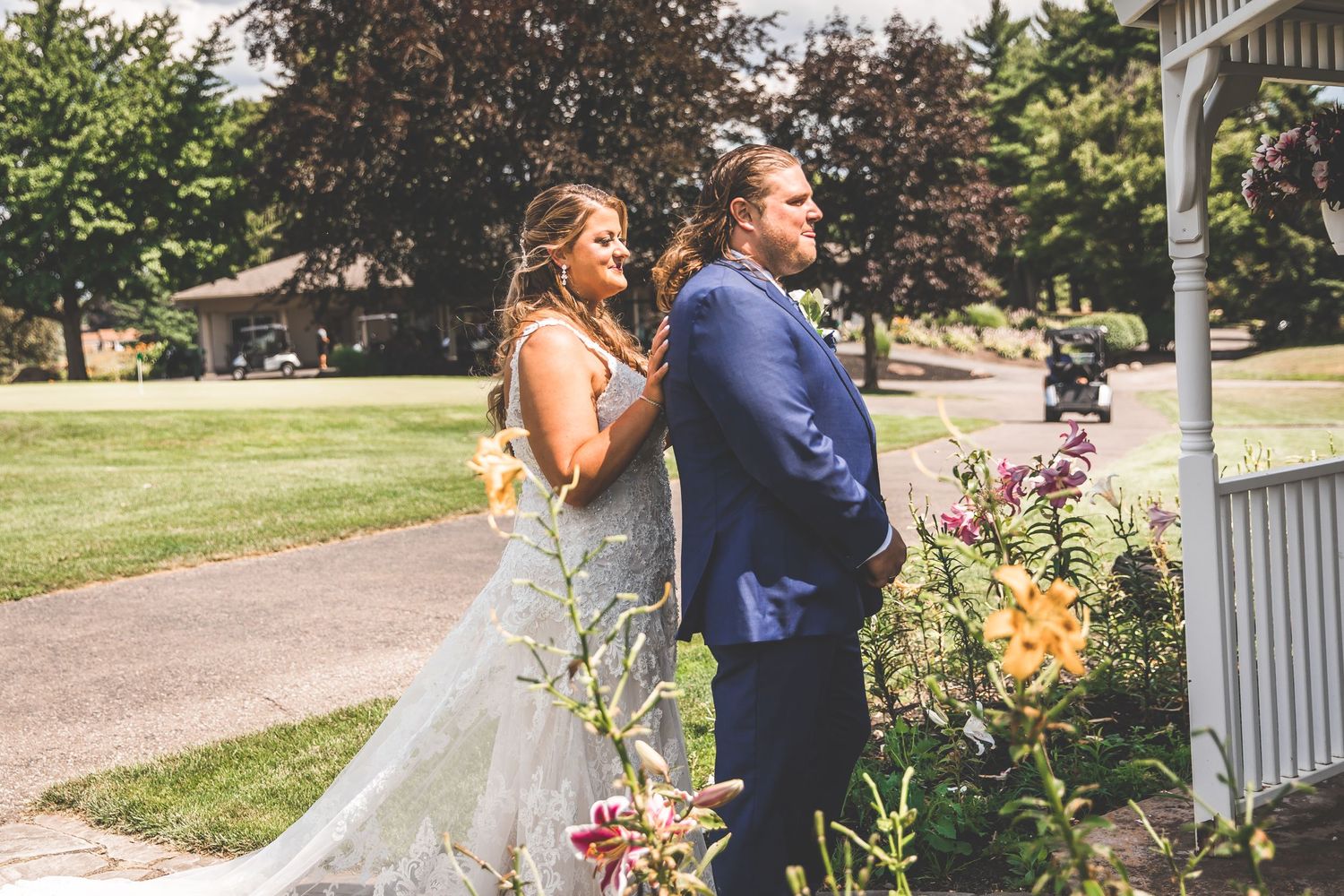 Romantic first look between couple in garden with white gazebo in background.