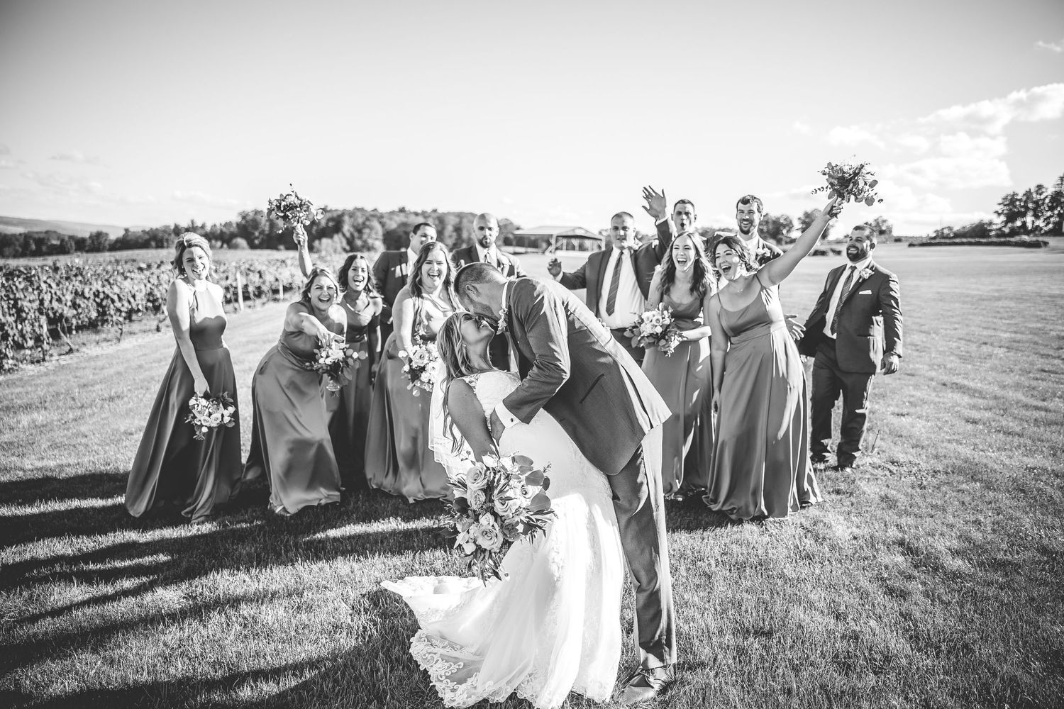 Black and white panorama of wedding party procession across vineyard grounds during reception.