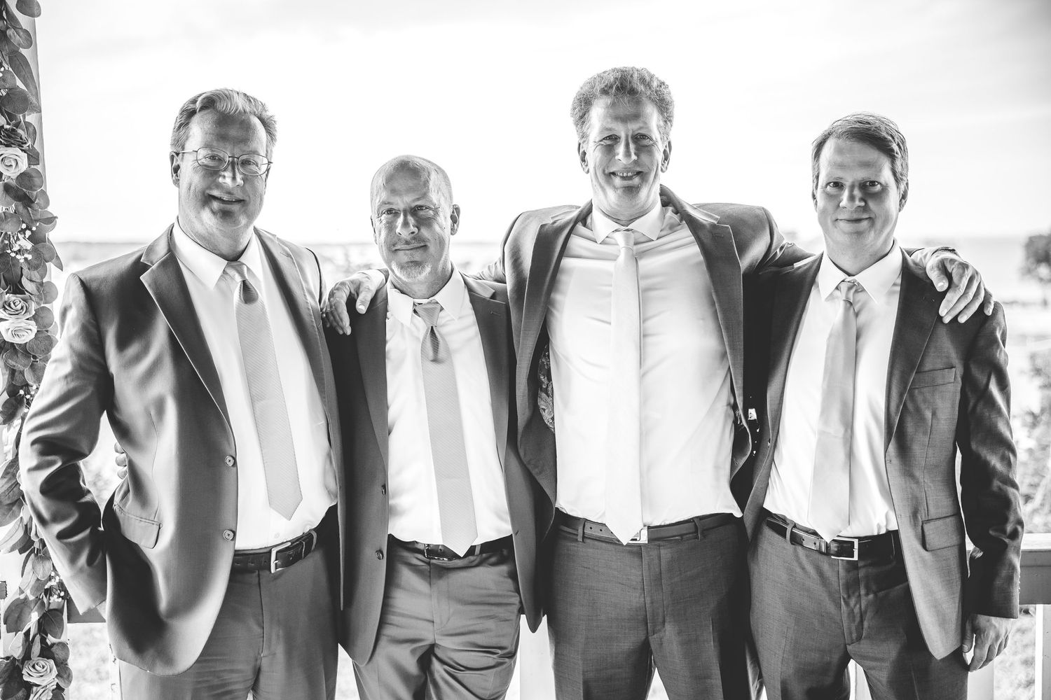 Black and white portrait of groomsmen in formal attire smiling together.