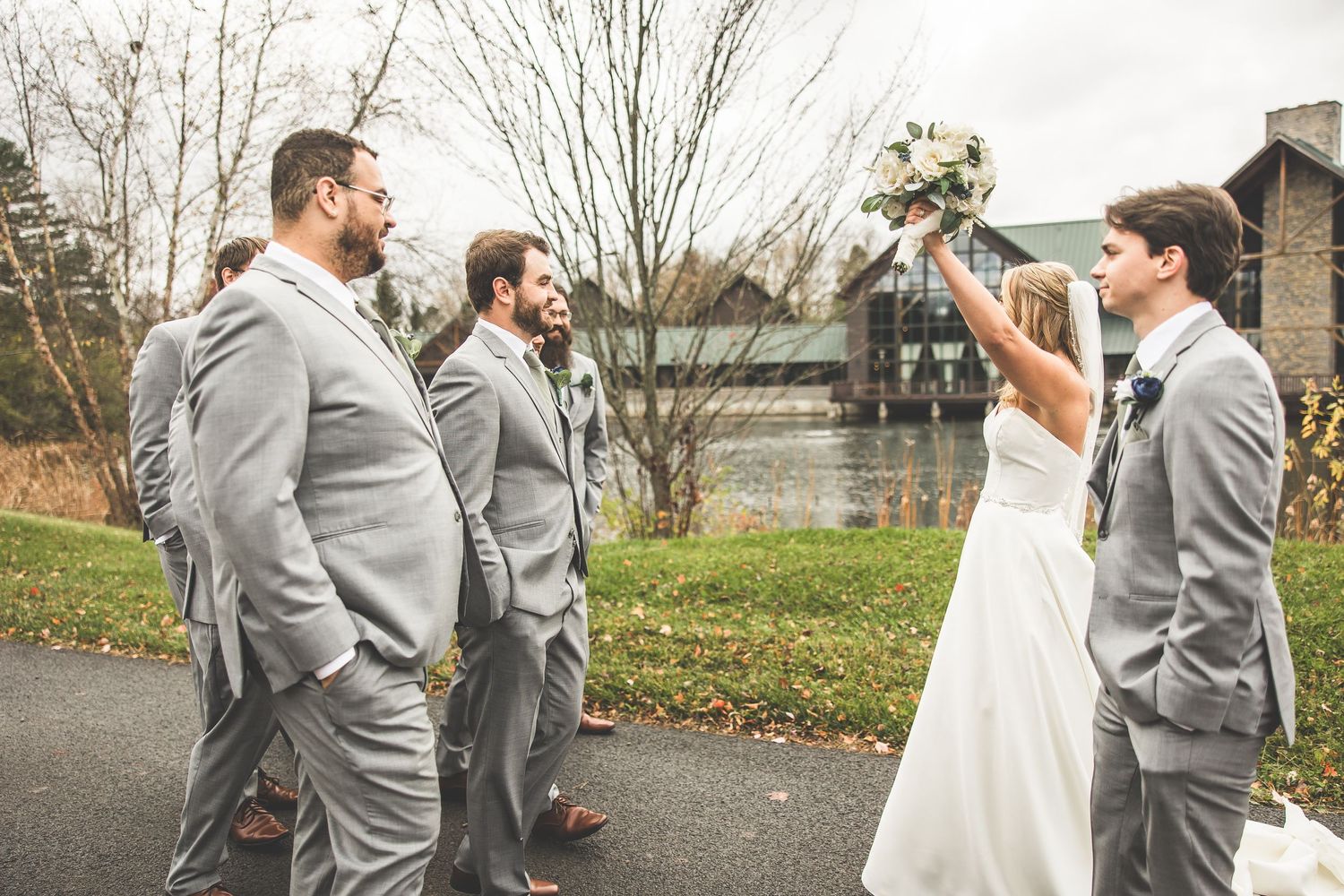 Wedding party members in gray suits and formal attire pose outdoors.