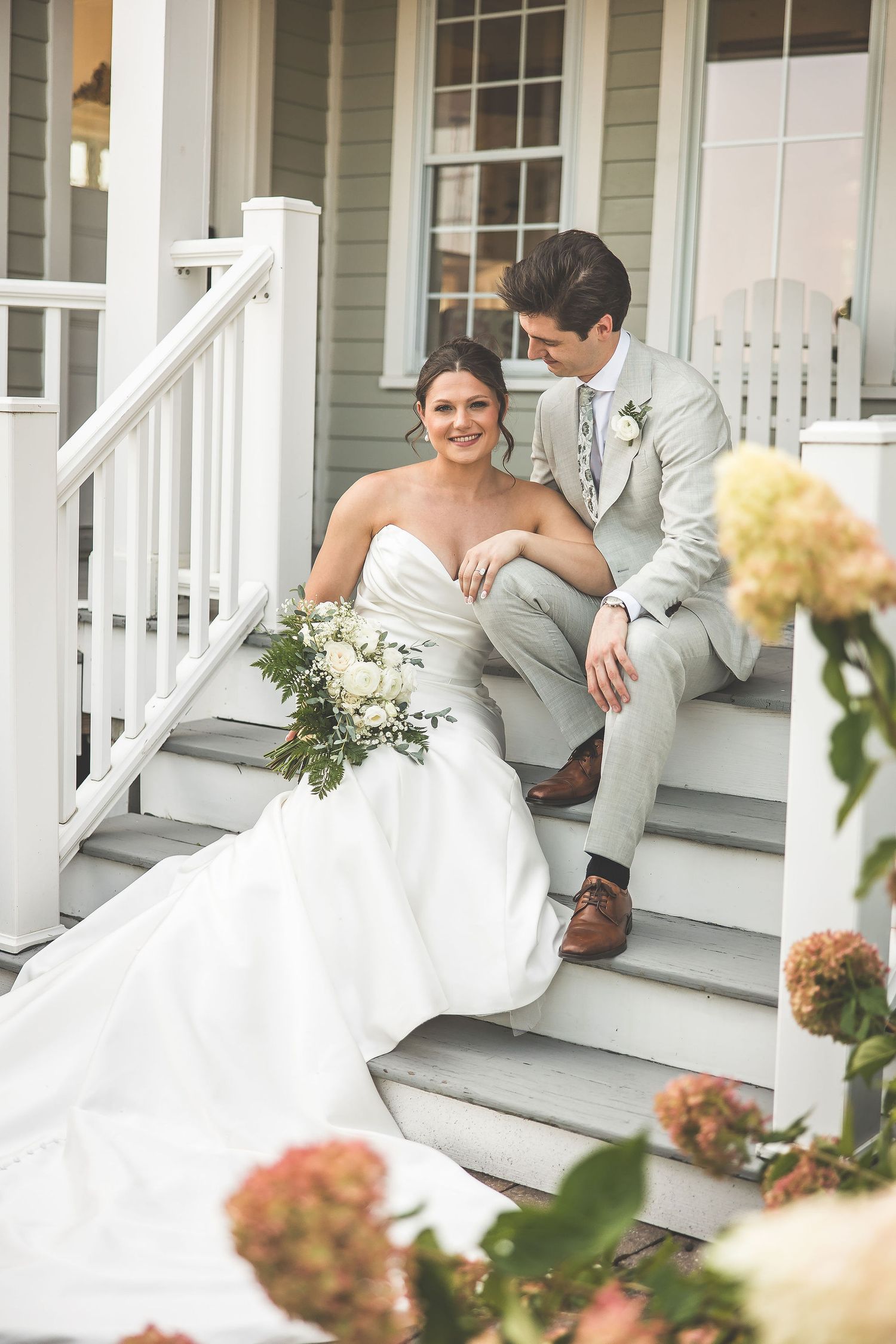 Romantic moment captured on a front porch with blooming flowers and white railings.