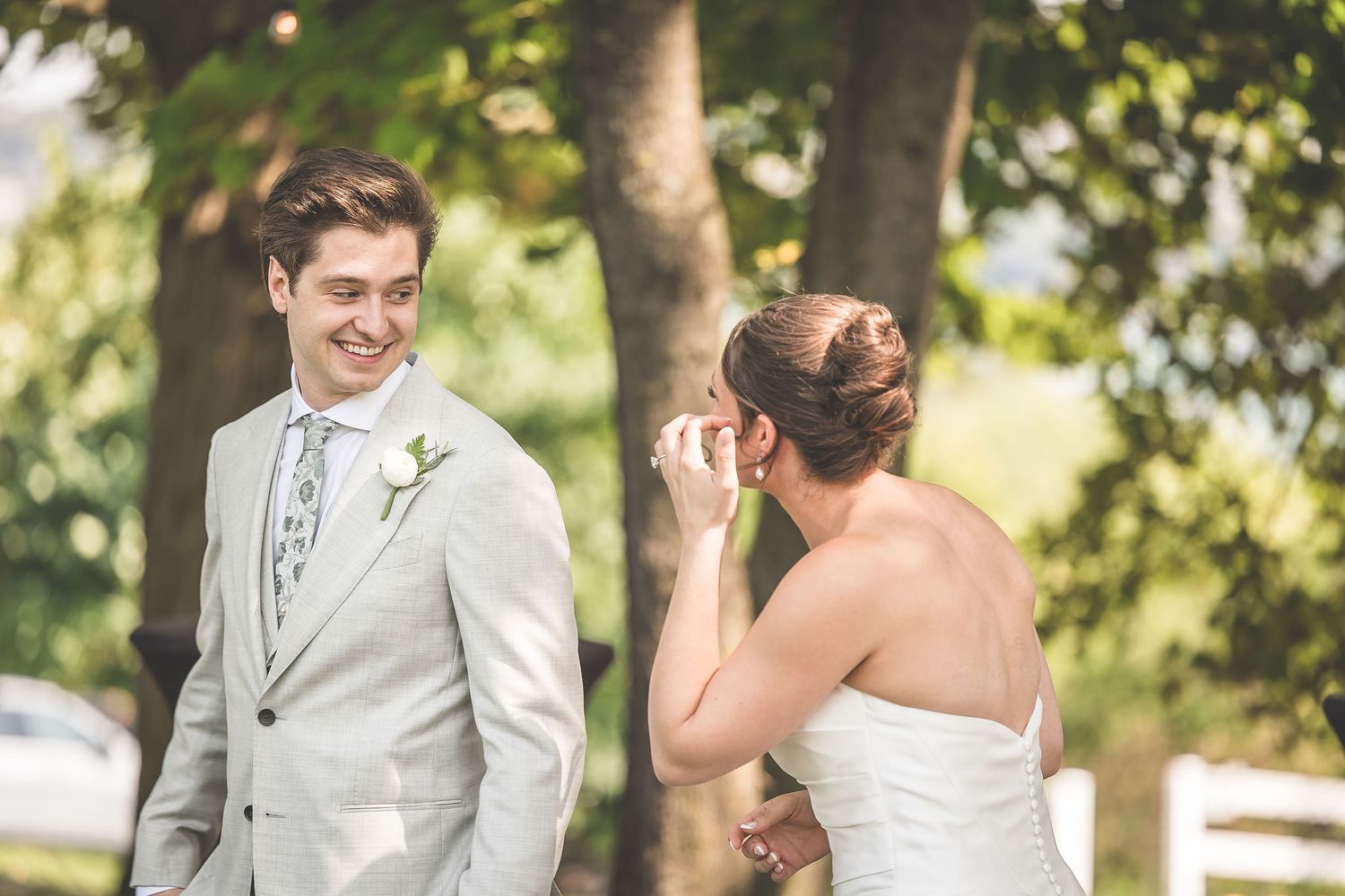 Candid wedding moments photographed under the shade of leafy green trees.