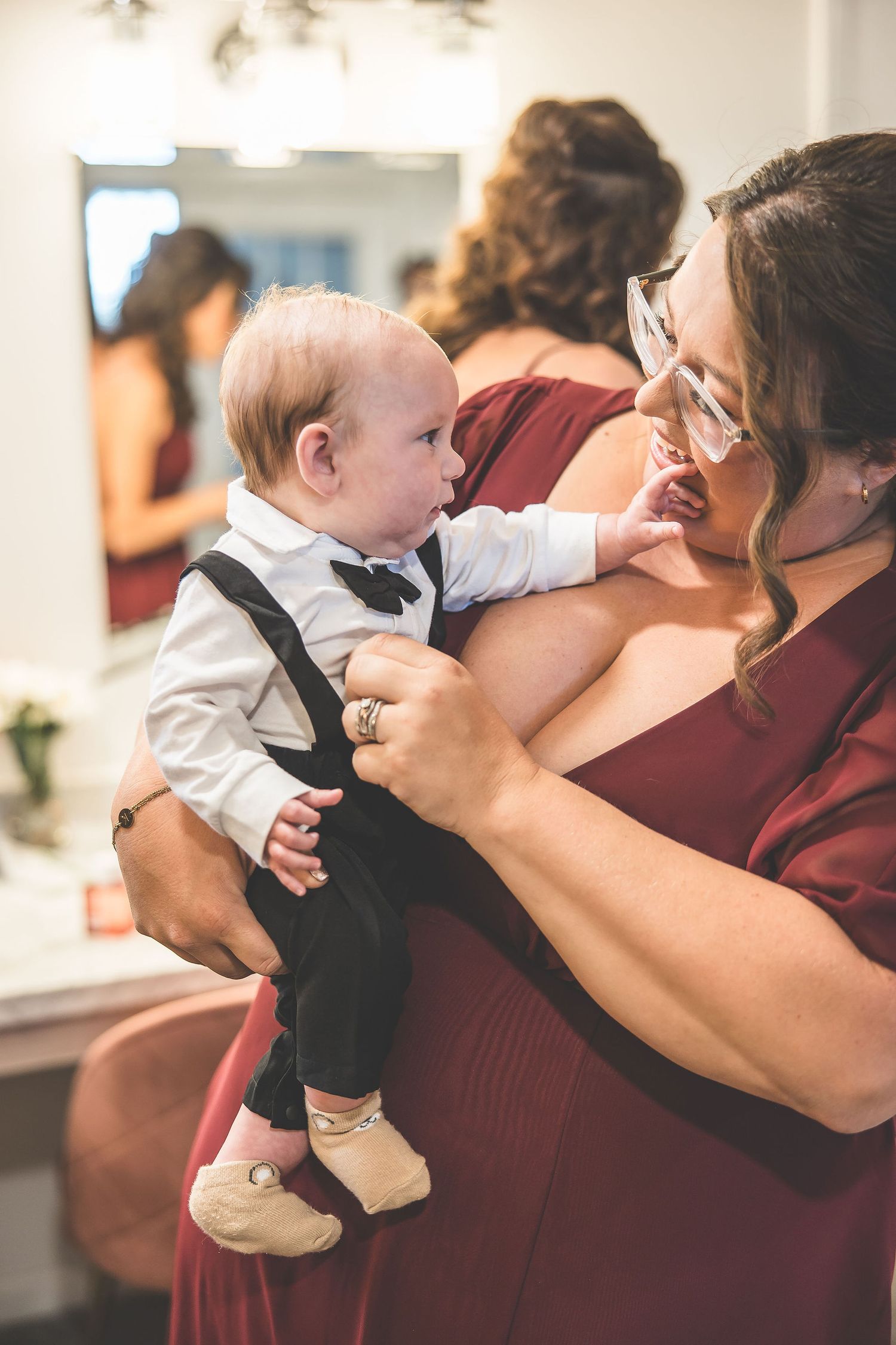 Tender moment between wedding party members in burgundy attire.