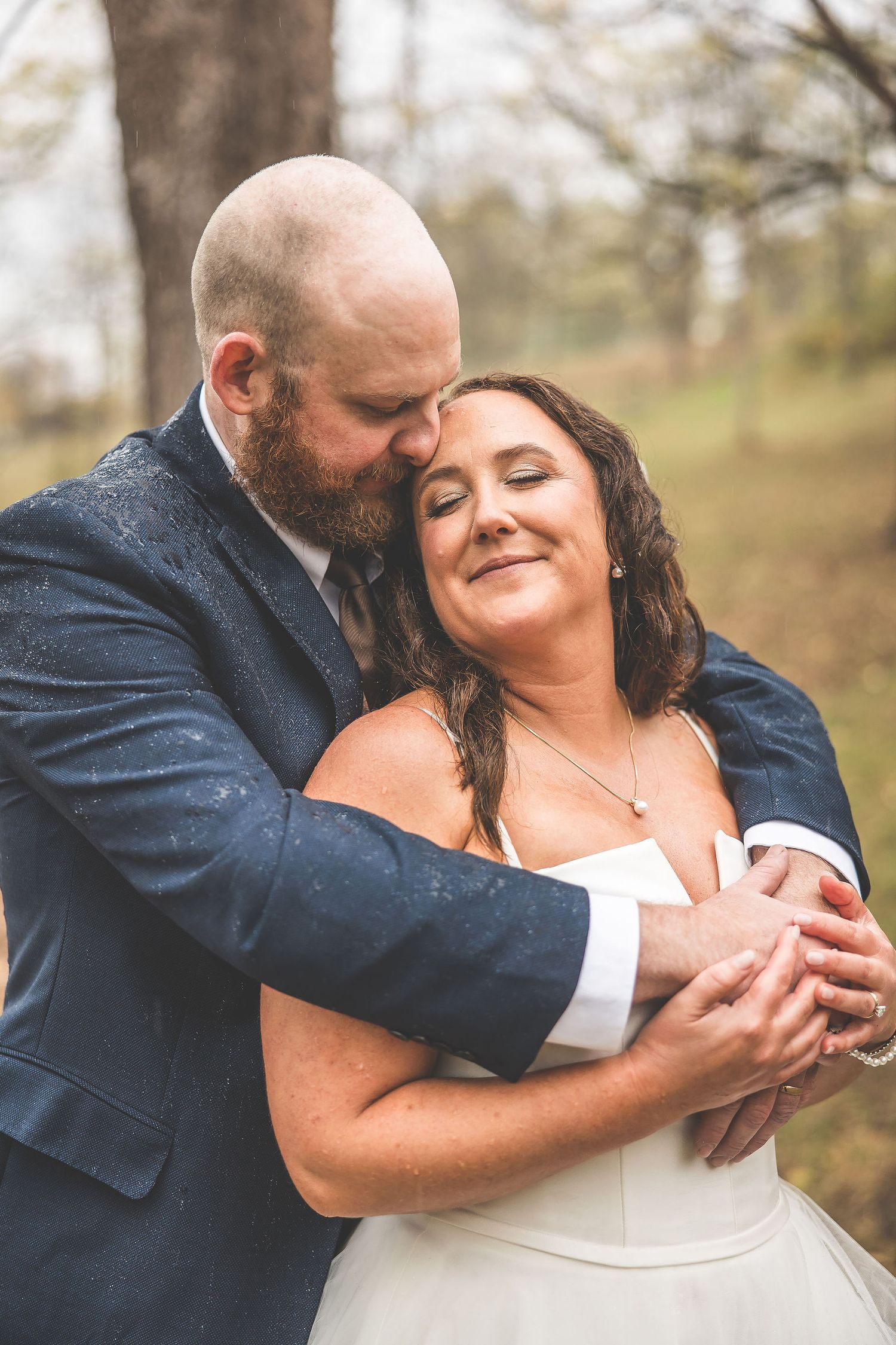 An intimate wedding portrait showing a close embrace in a natural autumn setting.