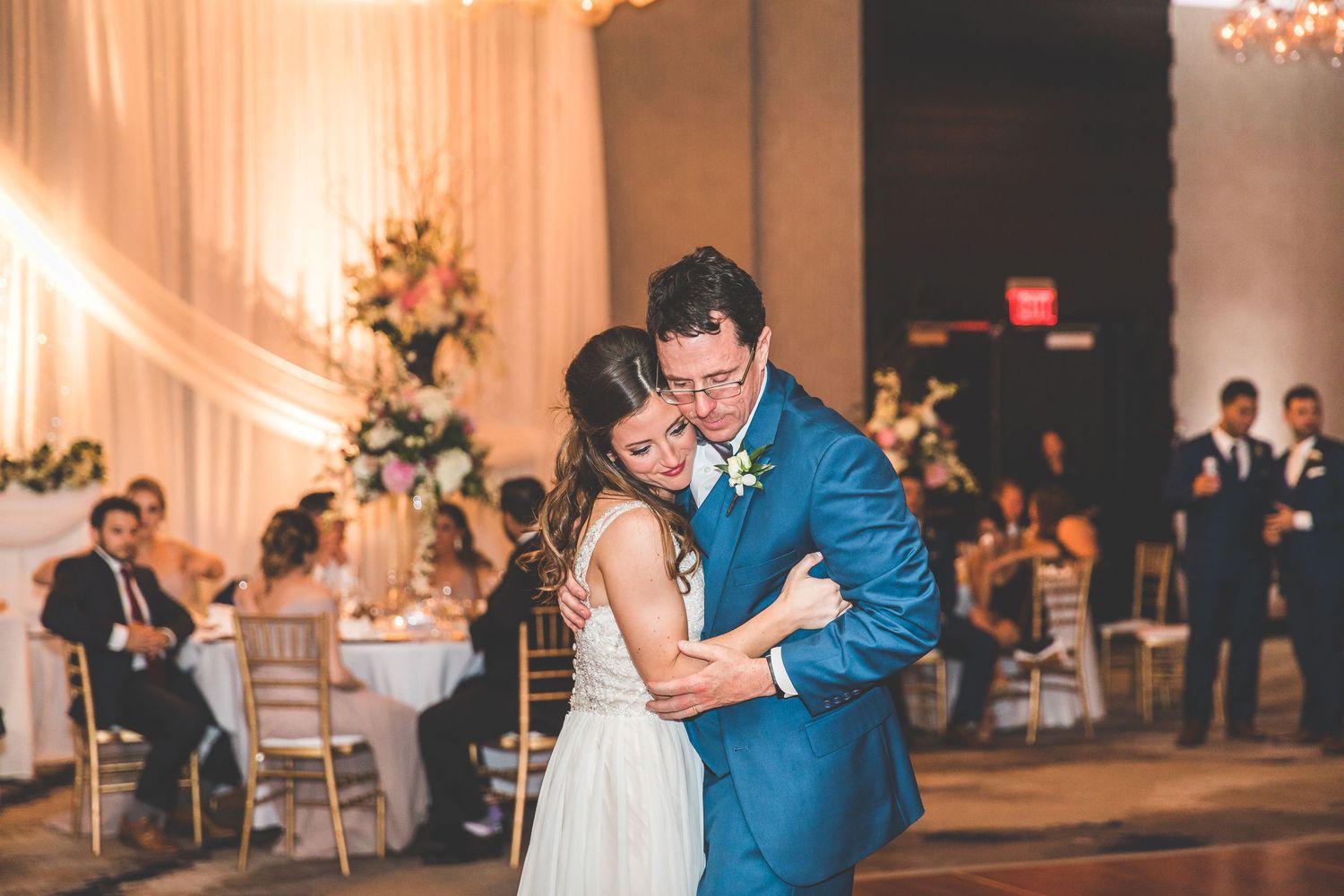 Elegant ballroom wedding reception with white draping and chandeliers.