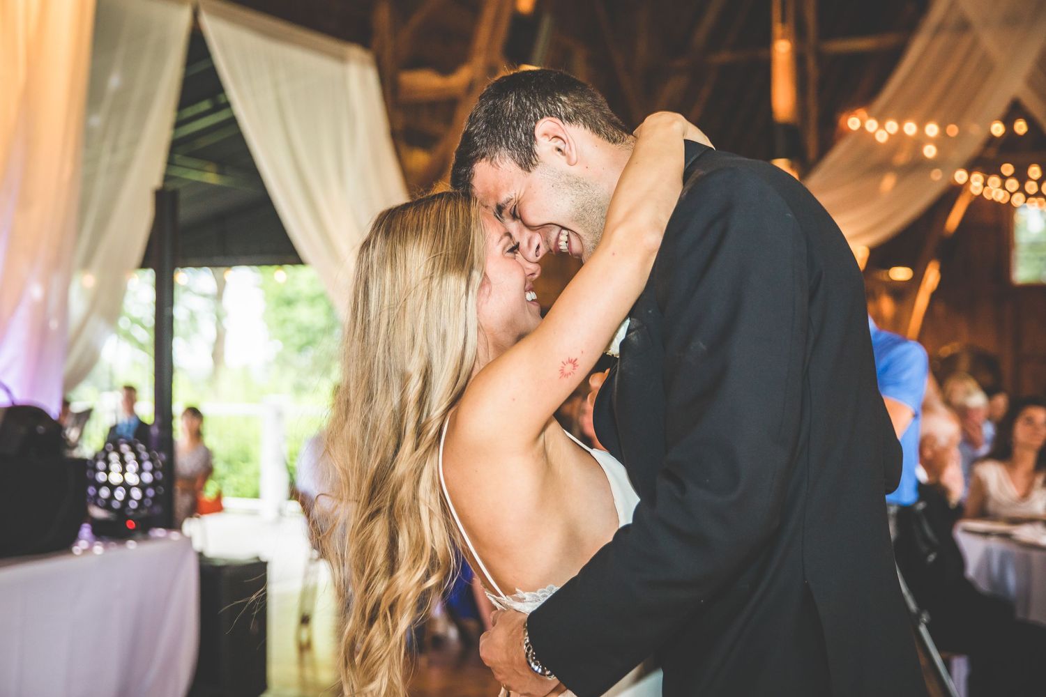 Newlyweds share an intimate dance moment under warm lighting in a decorated wedding reception venue.