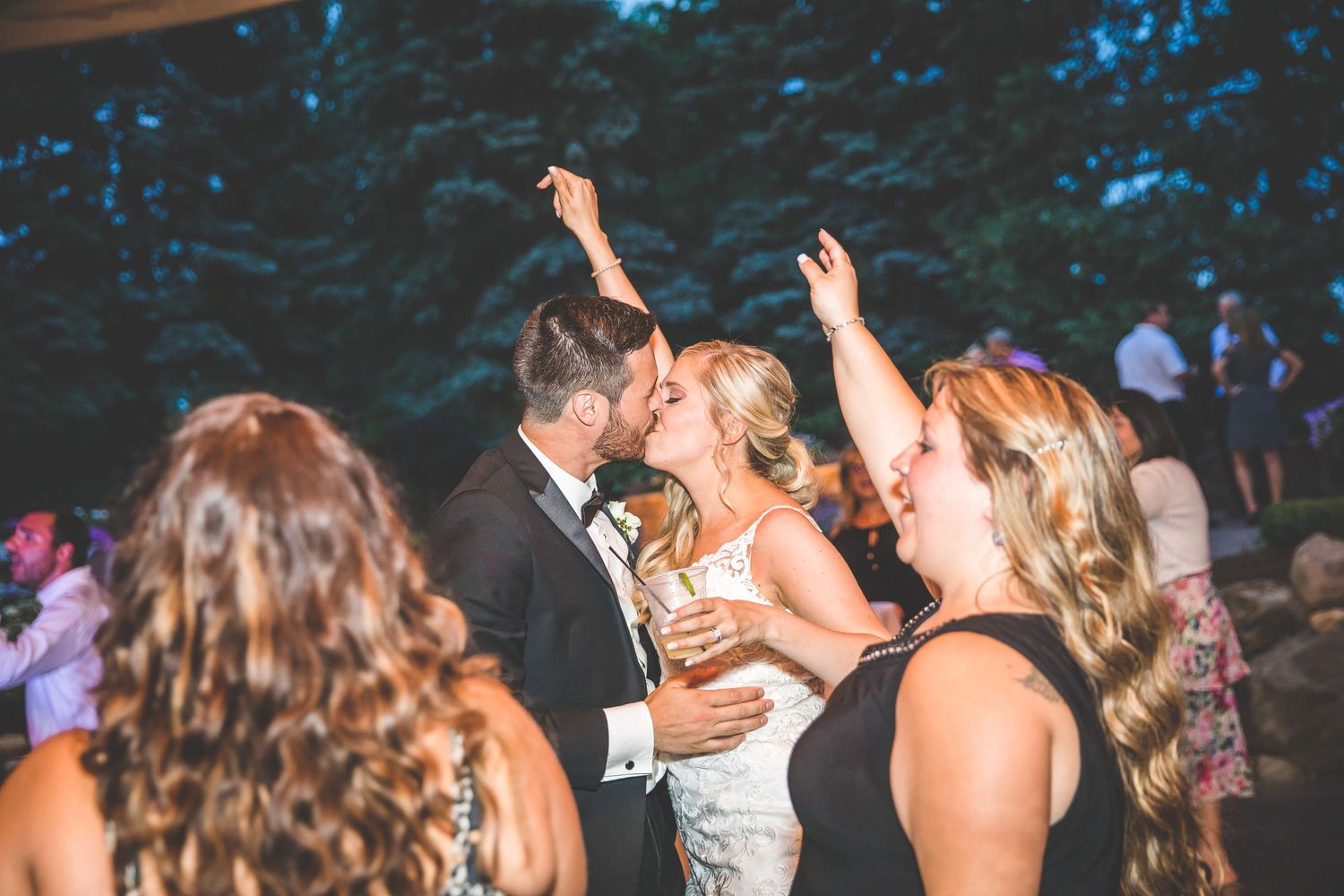Wedding reception dance party with dramatic lighting and guests enjoying the celebration.