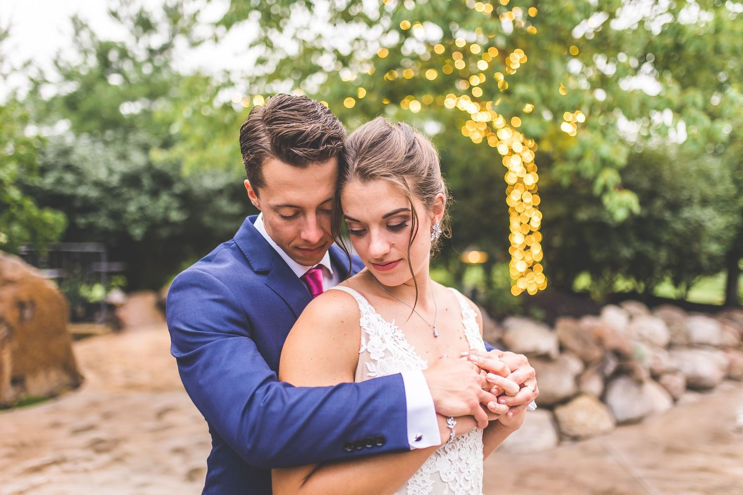 Couple shares a romantic moment during their outdoor wedding reception with twinkle lights in the background.