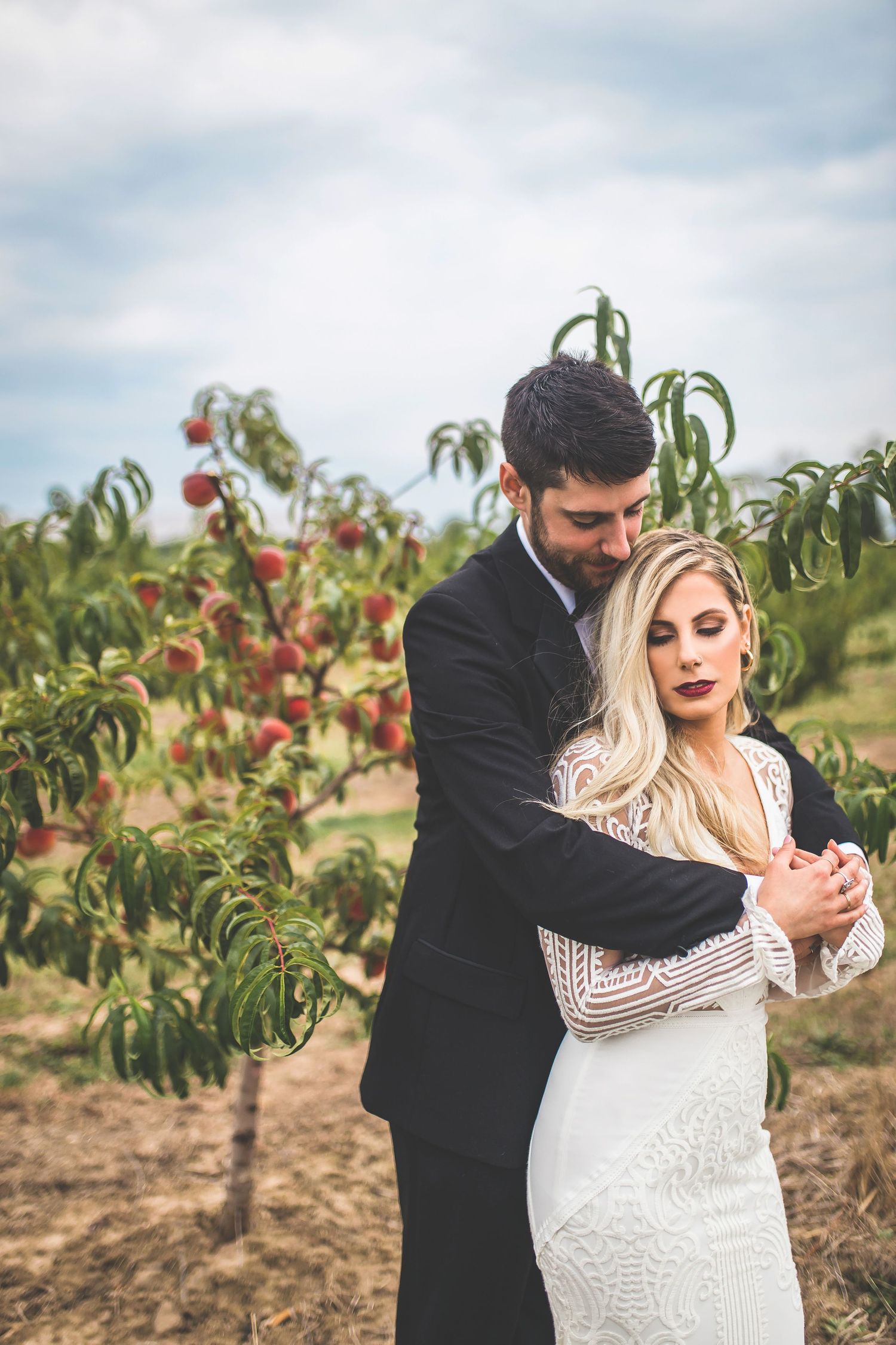 Couple dancing in an orchard with blooming fruit trees in the background.