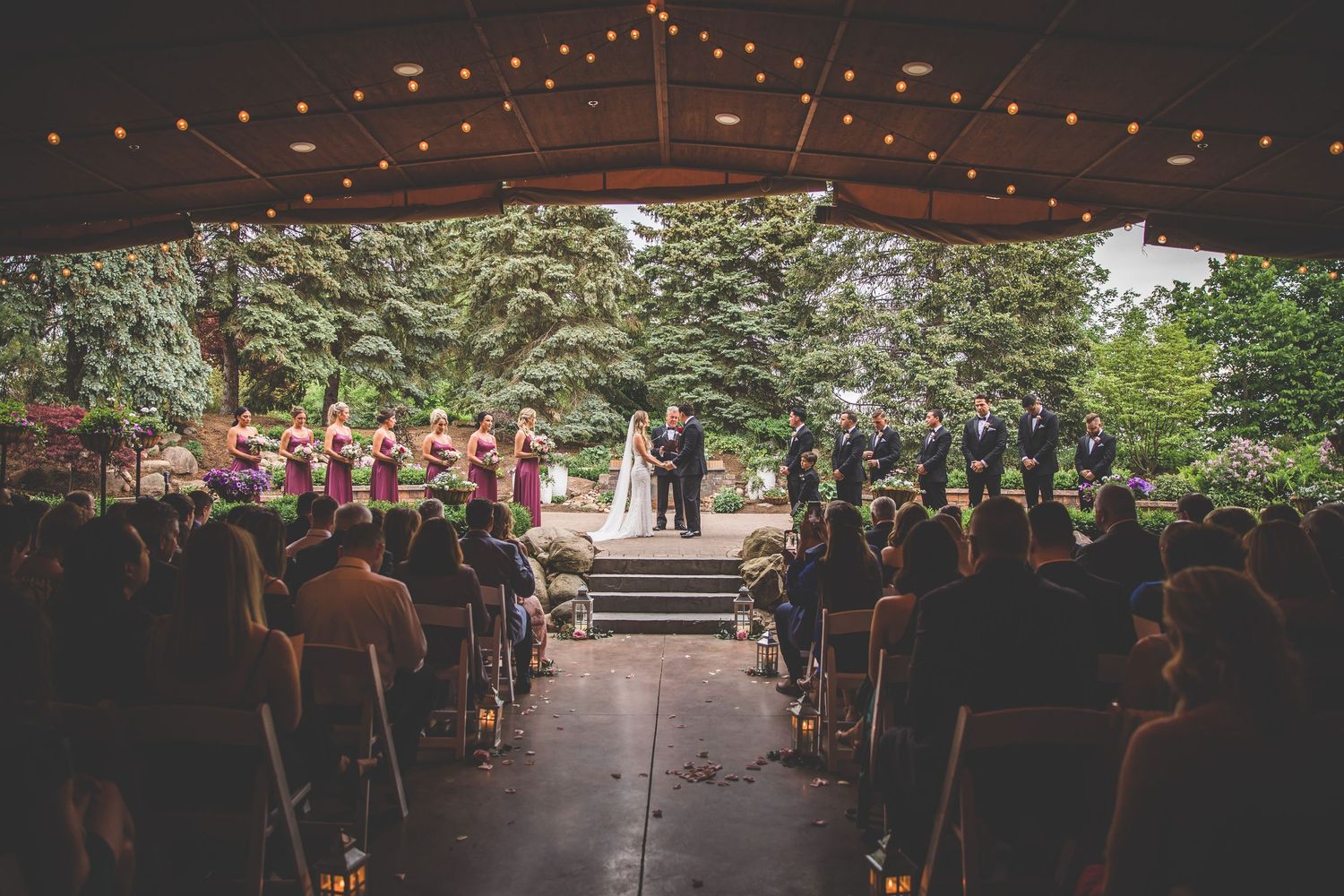 Wedding ceremony venue with string lights and guests seated in rows at dusk.