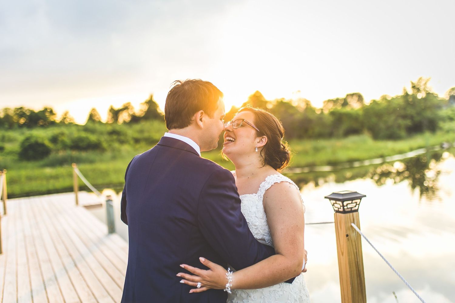 Romantic sunset portraits on a wooden dock with water and nature in the background.