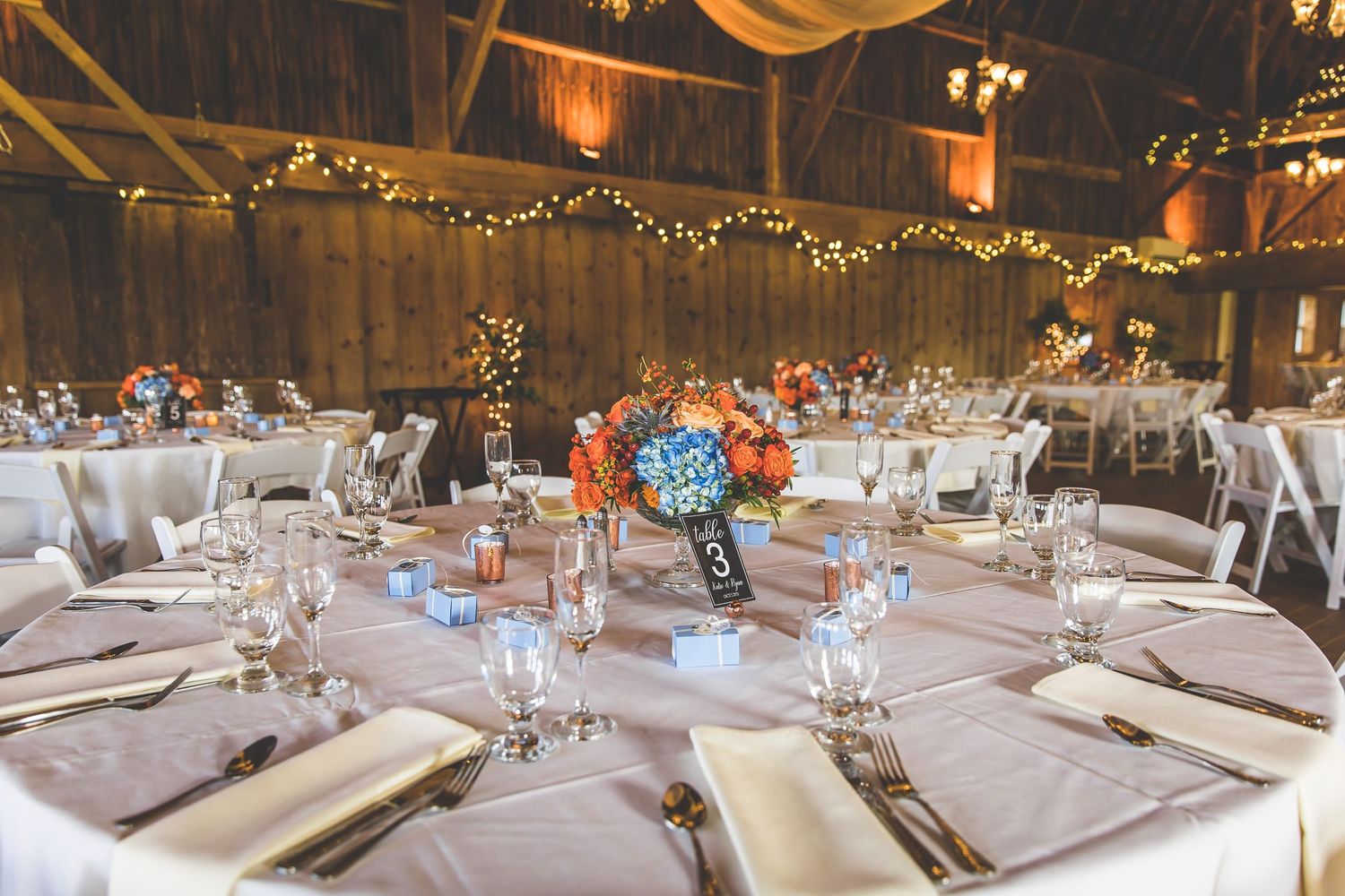Elegant barn wedding reception setup with round tables and floral centerpieces.