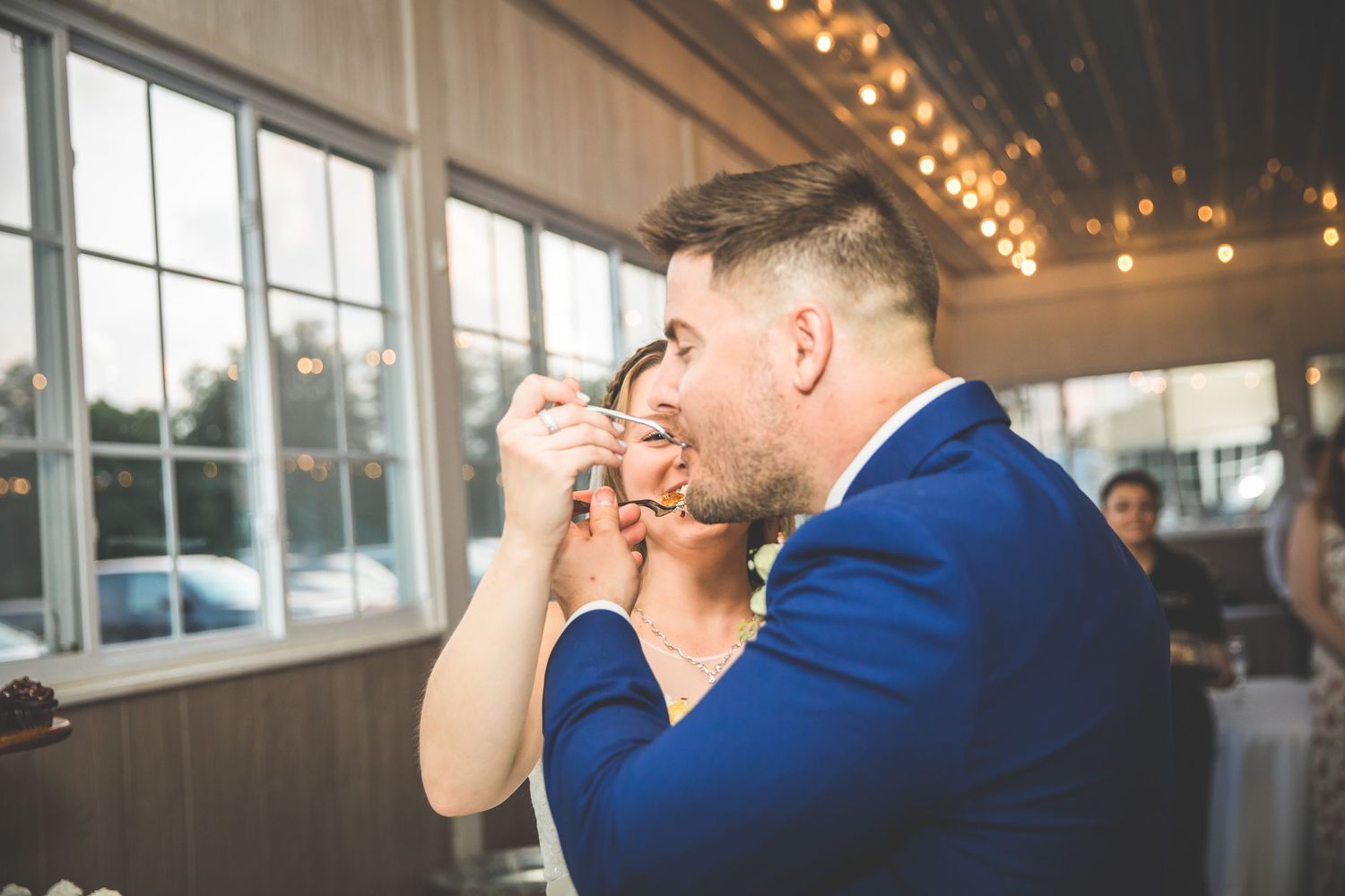 Candid moments between couple at reception venue with string lights.