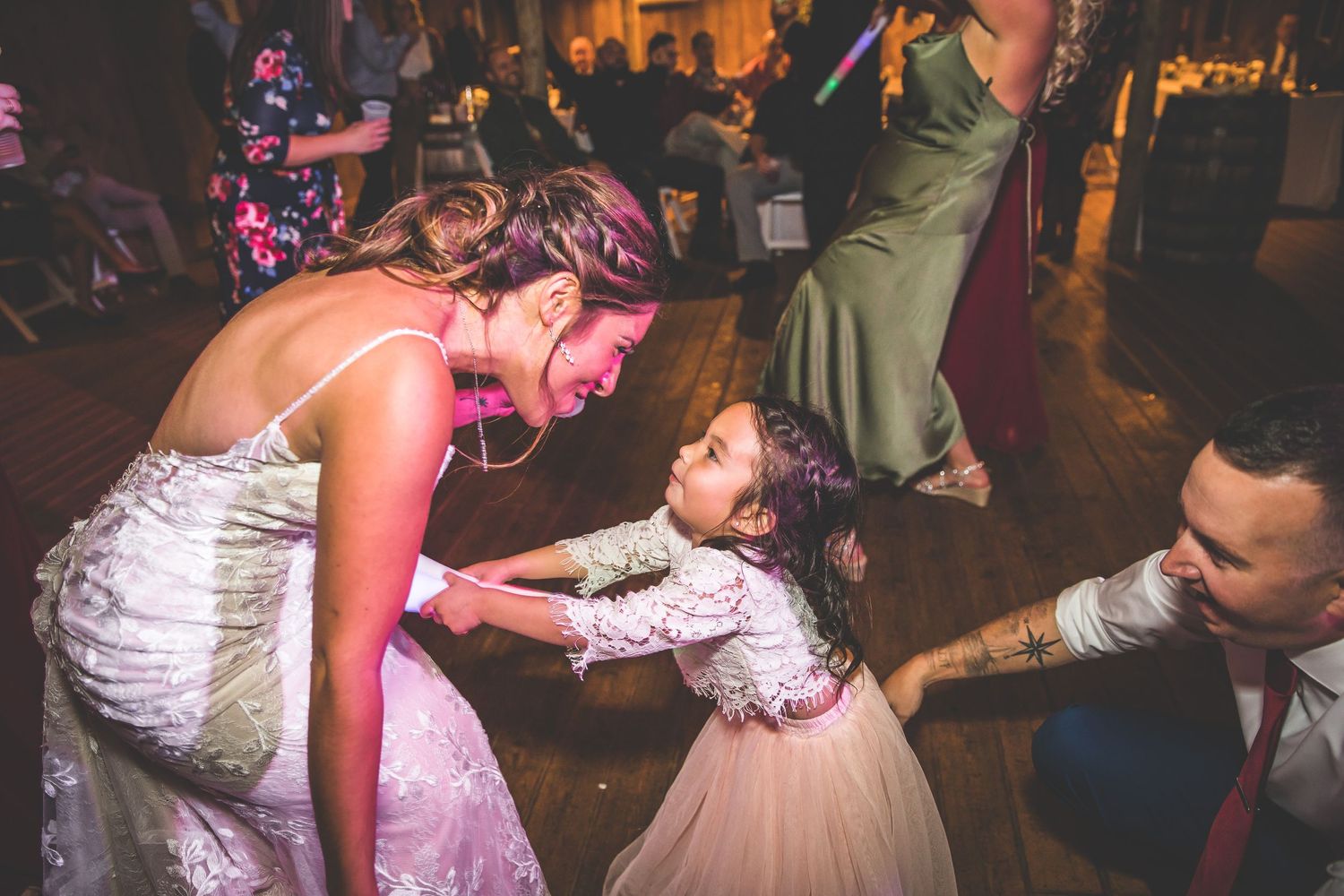 Couples twirling and dancing at a dimly lit wedding reception.