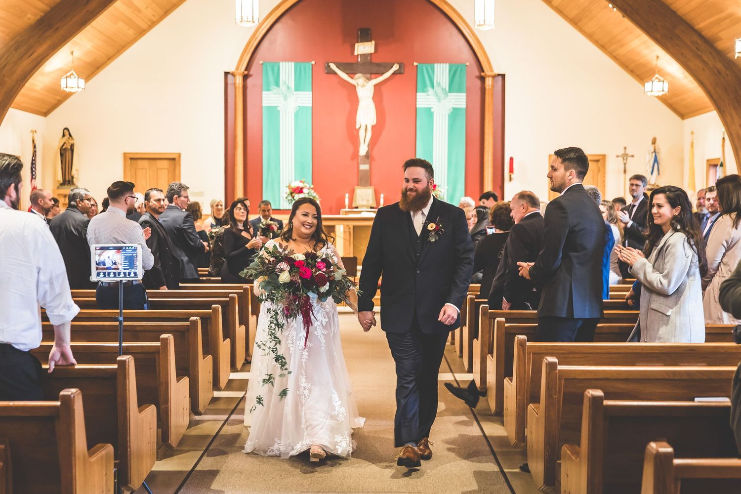 Church interior with wooden pews and religious symbols during a wedding ceremony.
