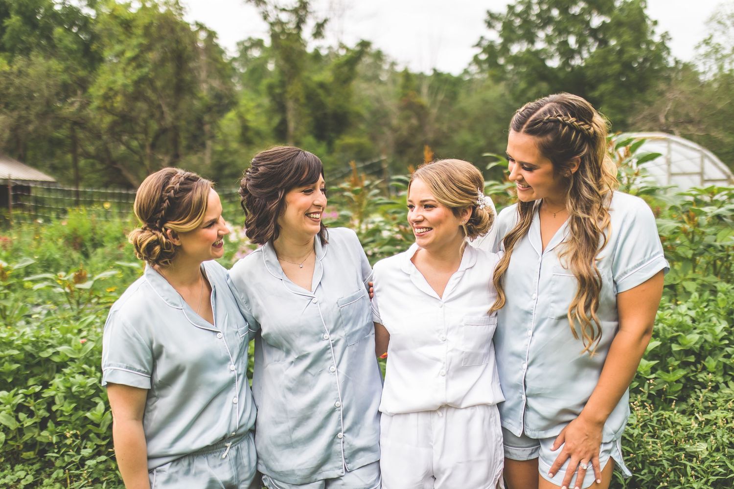 Wedding party in casual attire walking through a garden setting.