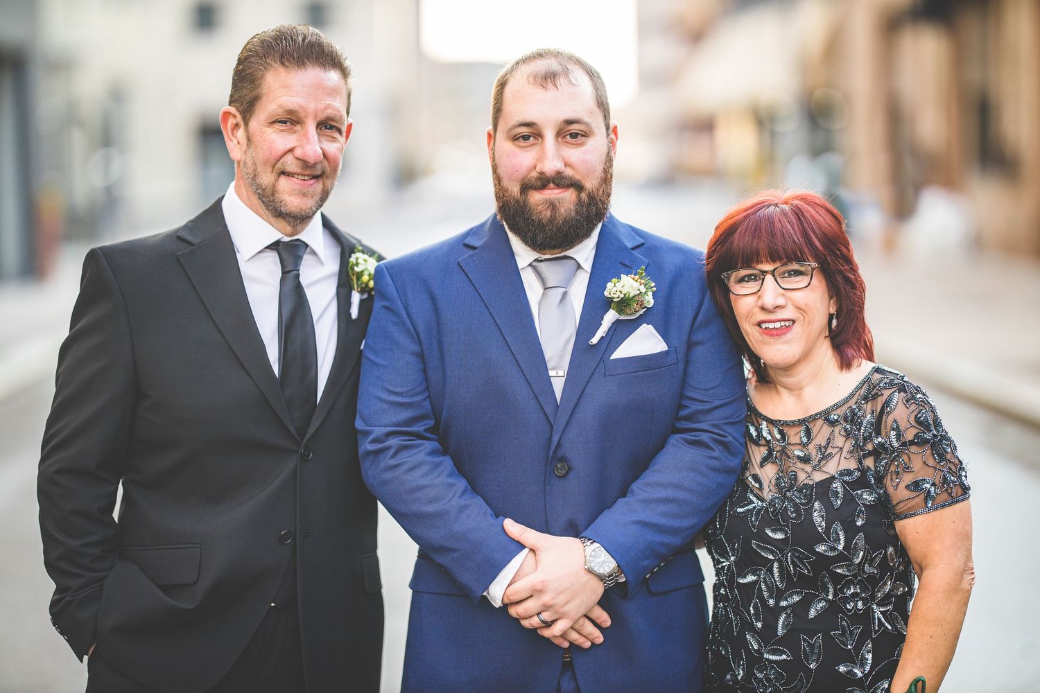 Wedding party members smile together on urban street.