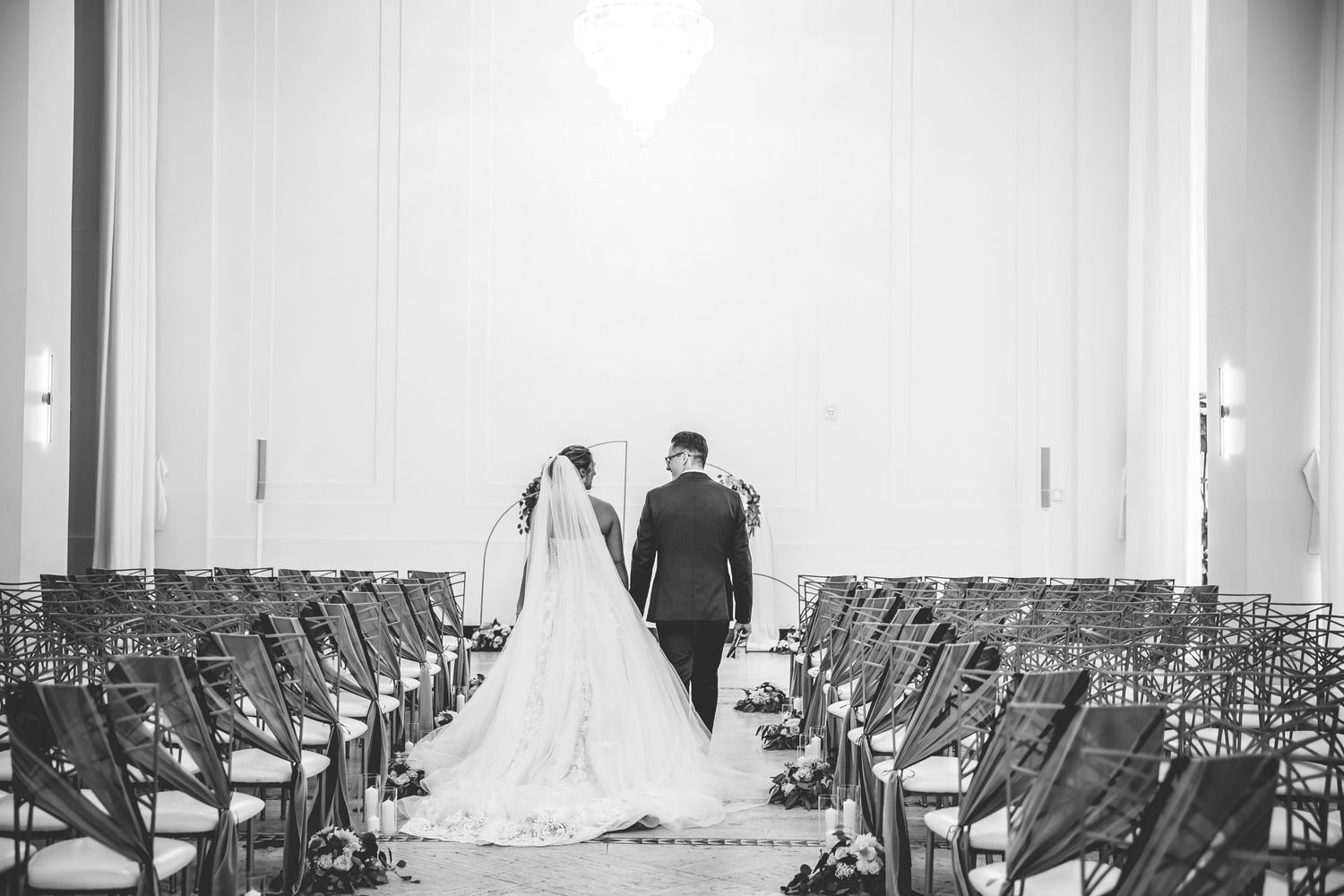 Empty ceremony chairs lined up in a white room before a wedding.
