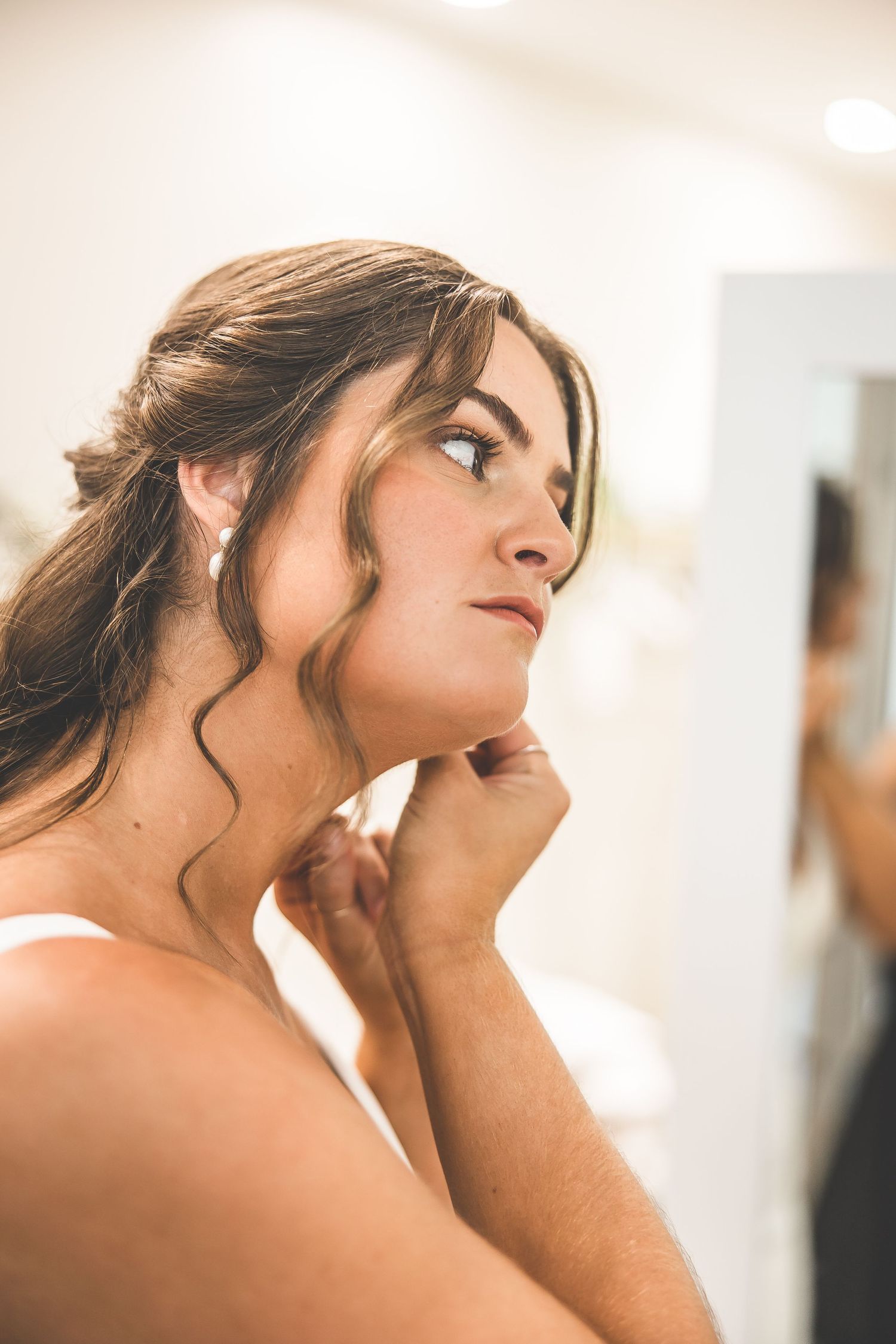 Side profile of a woman with an elegant updo and curled tendrils framing her face.