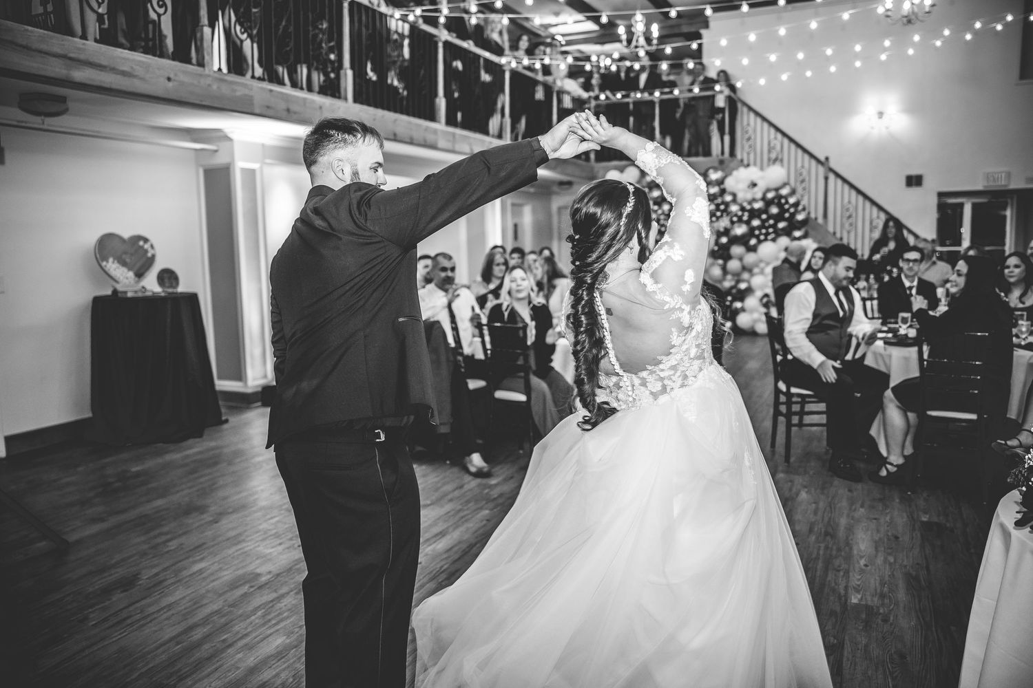 Wedding couple dancing and celebrating during their reception under string lights.