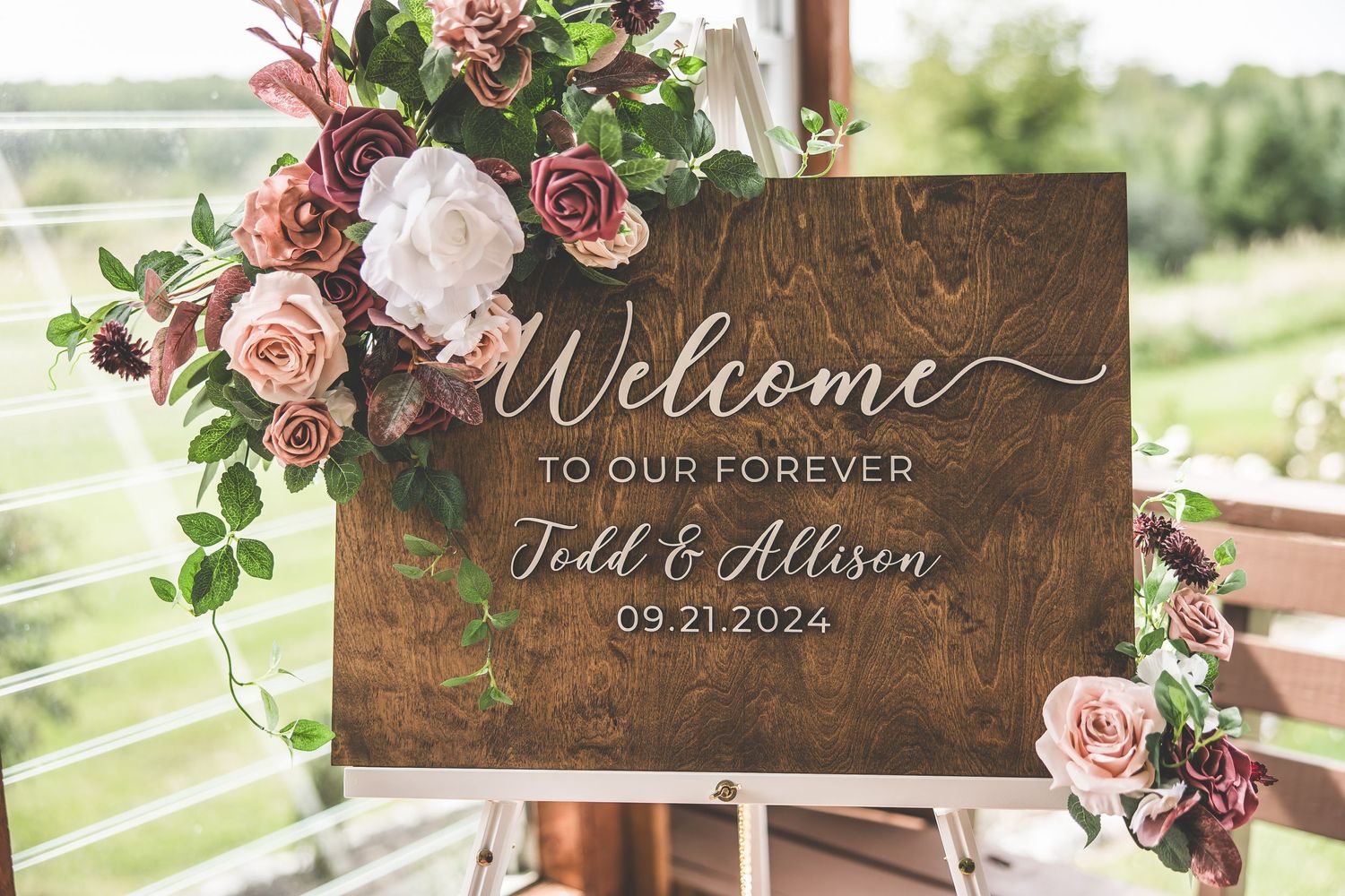 Wooden wedding welcome signs decorated with burgundy and pink roses.