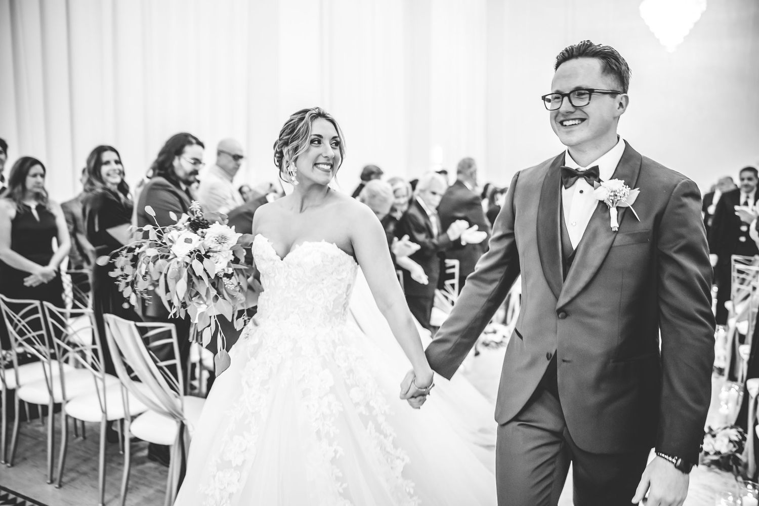 Black and white photo of couple sharing joyful moment during wedding ceremony in bright indoor venue.