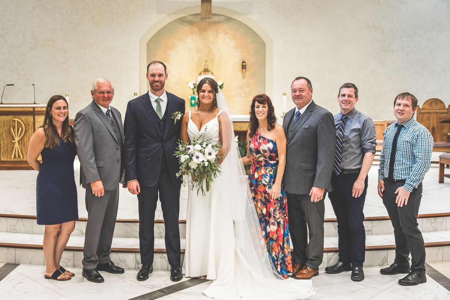 Formal wedding party portraits taken inside a church with traditional decor.