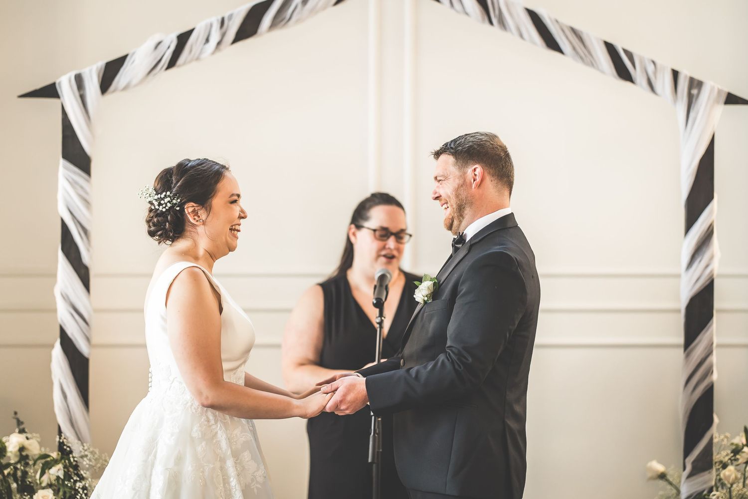 Intimate wedding ceremony moment in a bright indoor venue with decorative black and white accents.