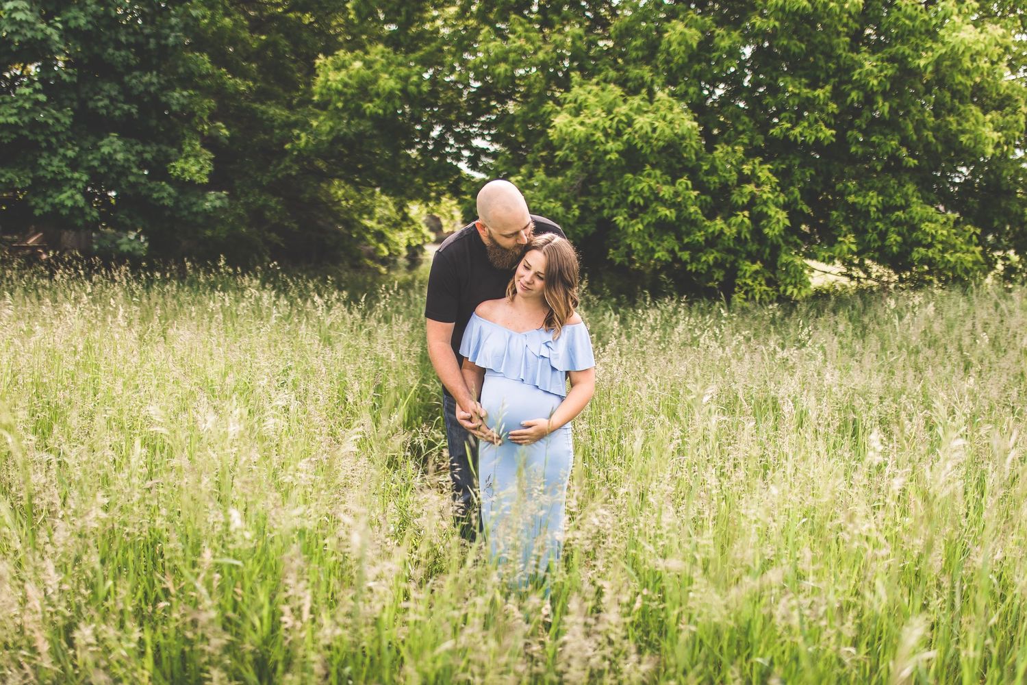 Natural outdoor family photo session in tall summer grass field.