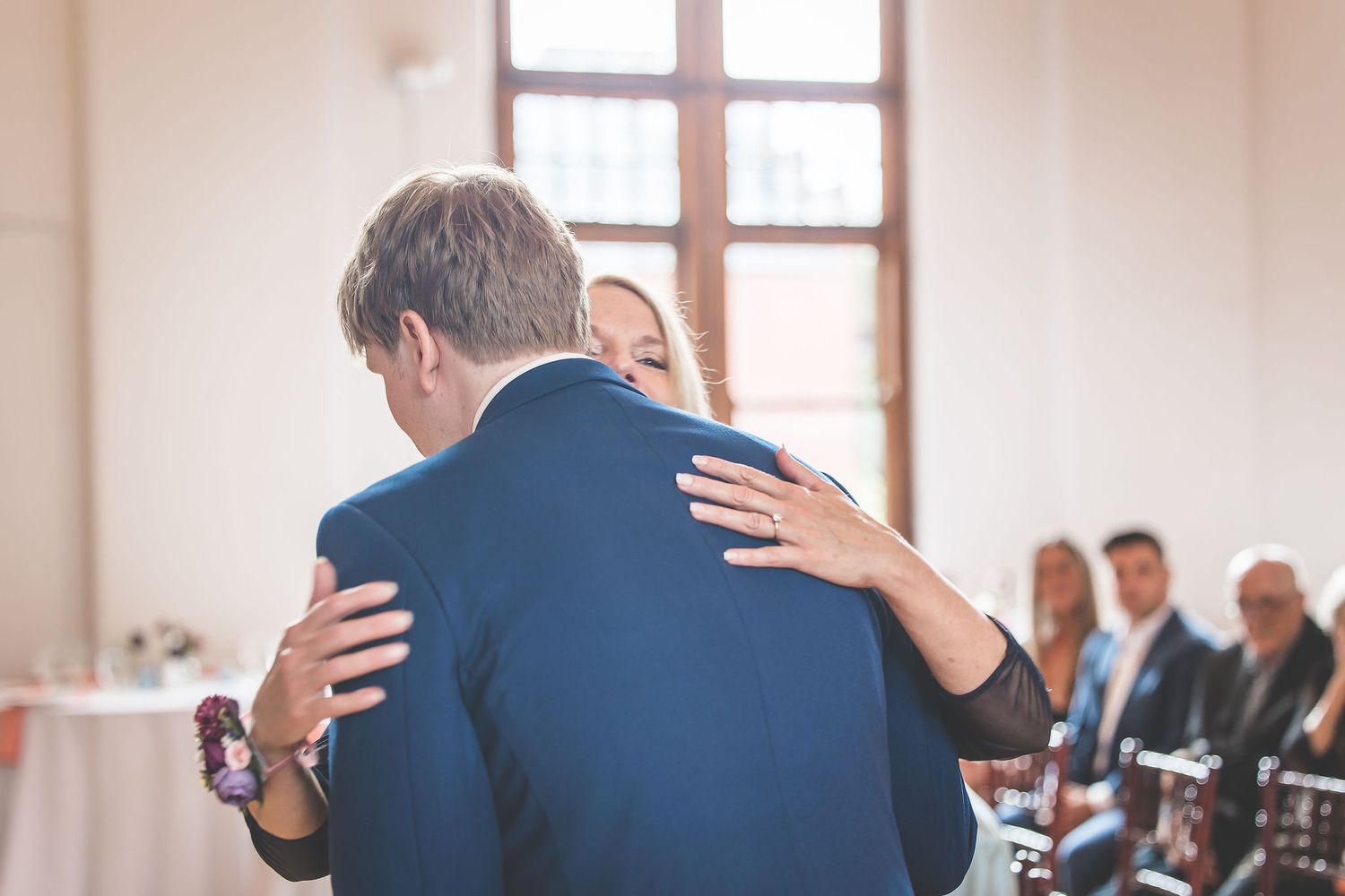 Emotional embrace captured during wedding ceremony in elegant indoor venue.