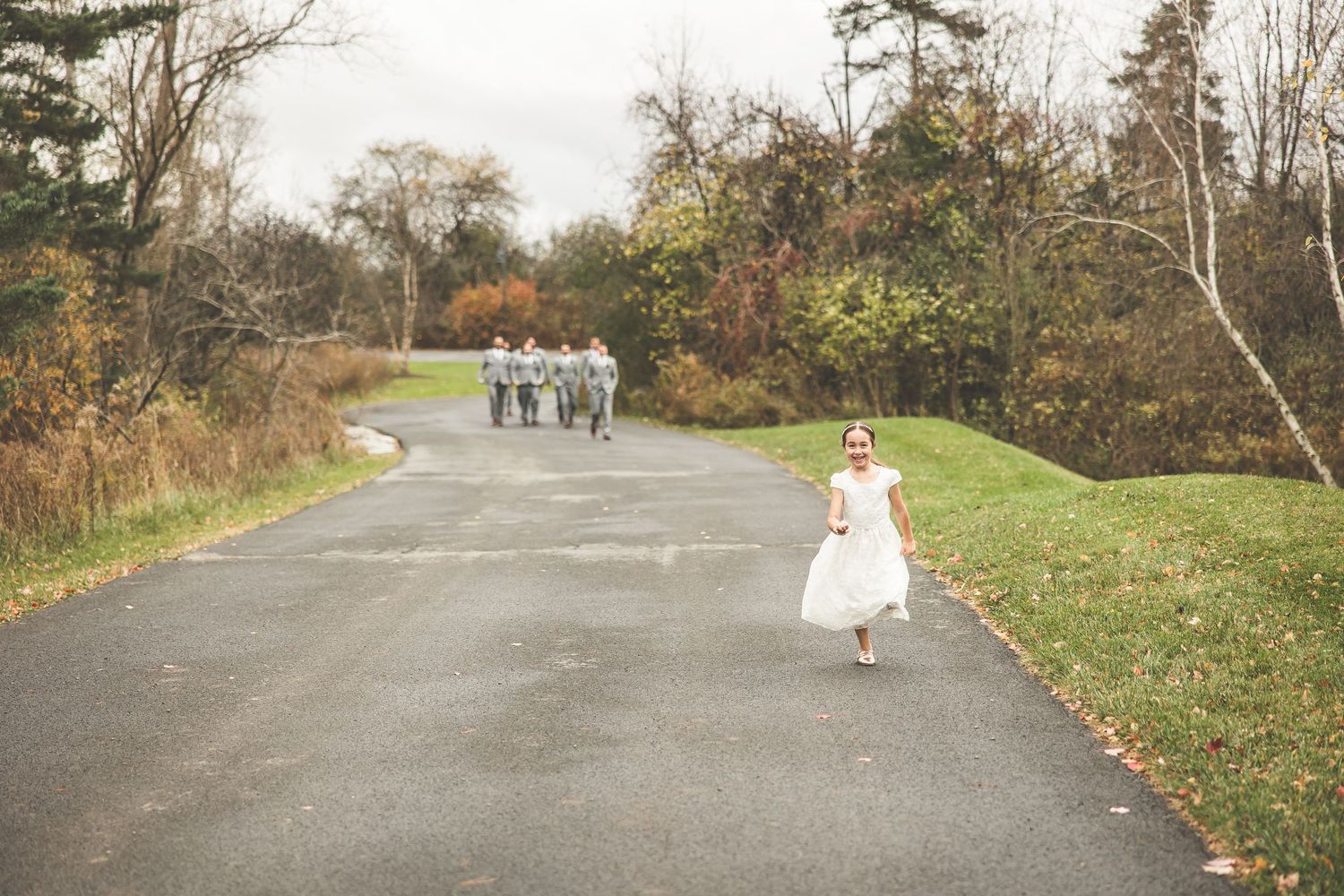 Long pathway shot of wedding party walking through autumn landscape.
