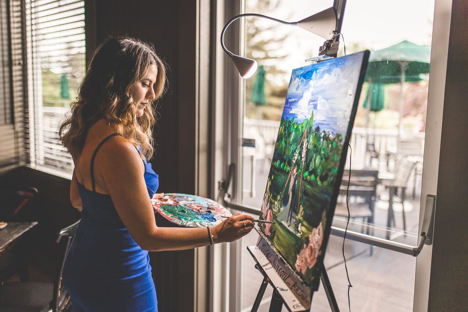 Artist painting on canvas in a bright studio space during a wedding event.