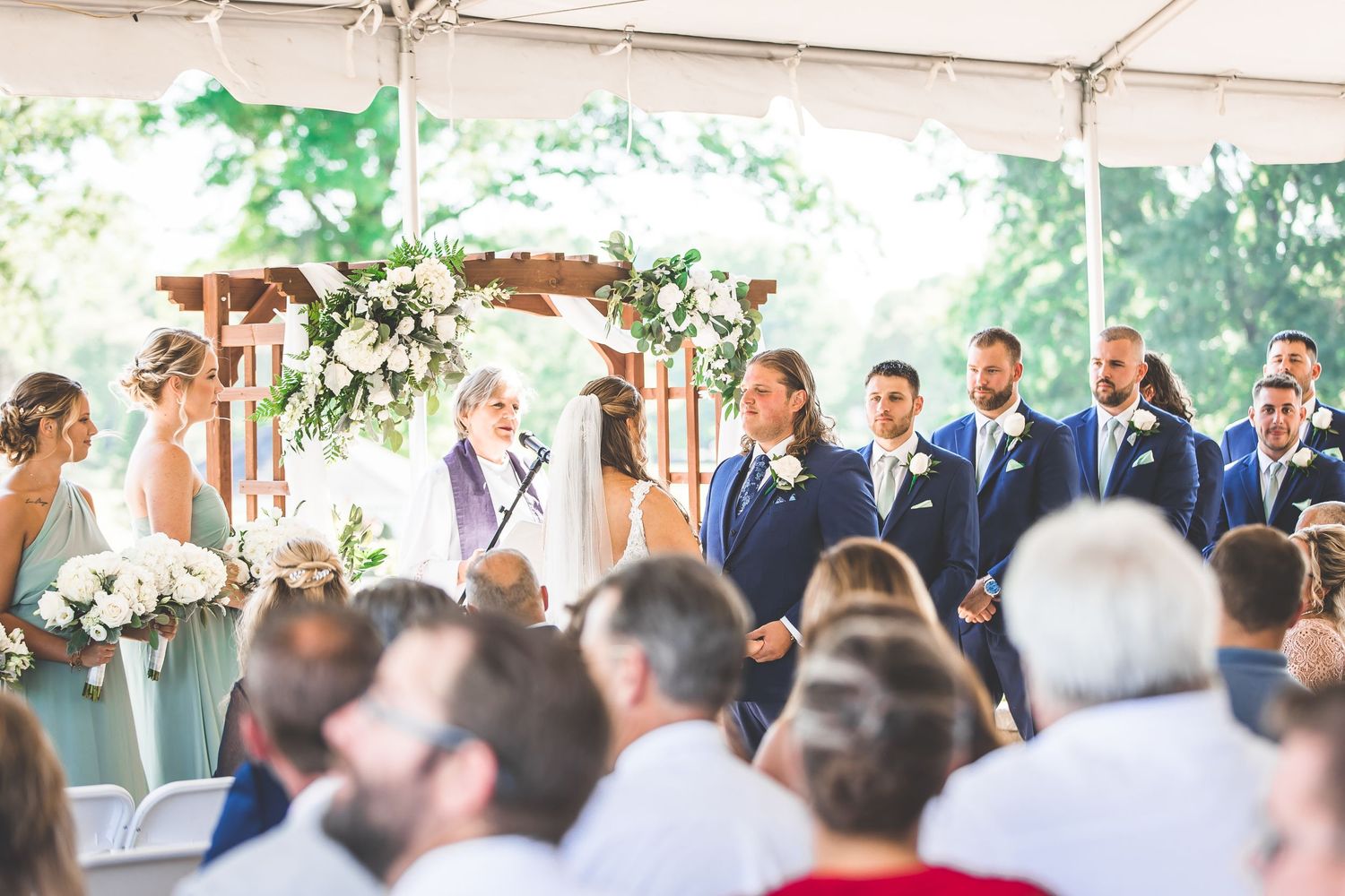 Wide angle shot of outdoor wedding ceremony with floral decorations and seated guests.