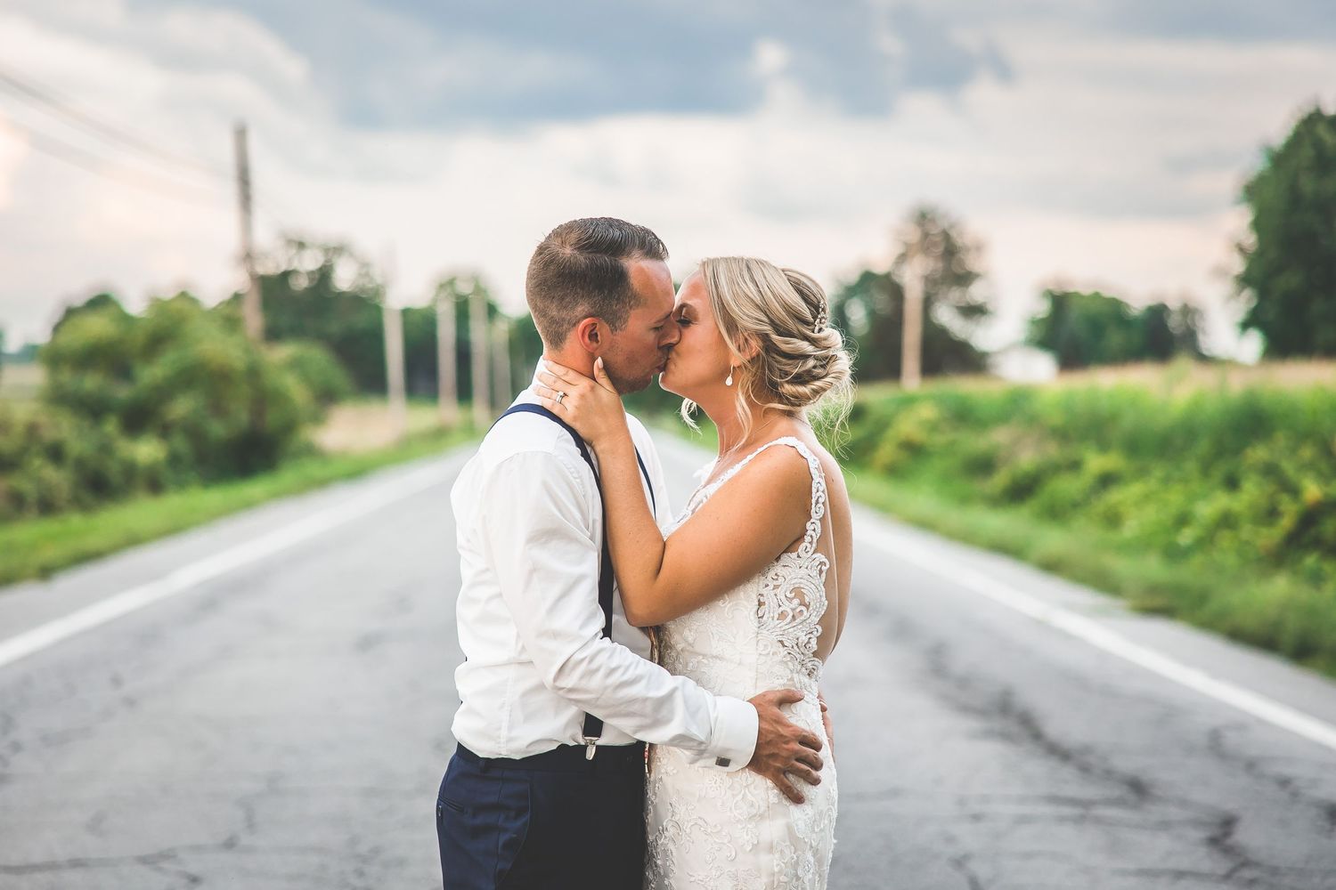 A romantic embrace between newlyweds on an empty country road.