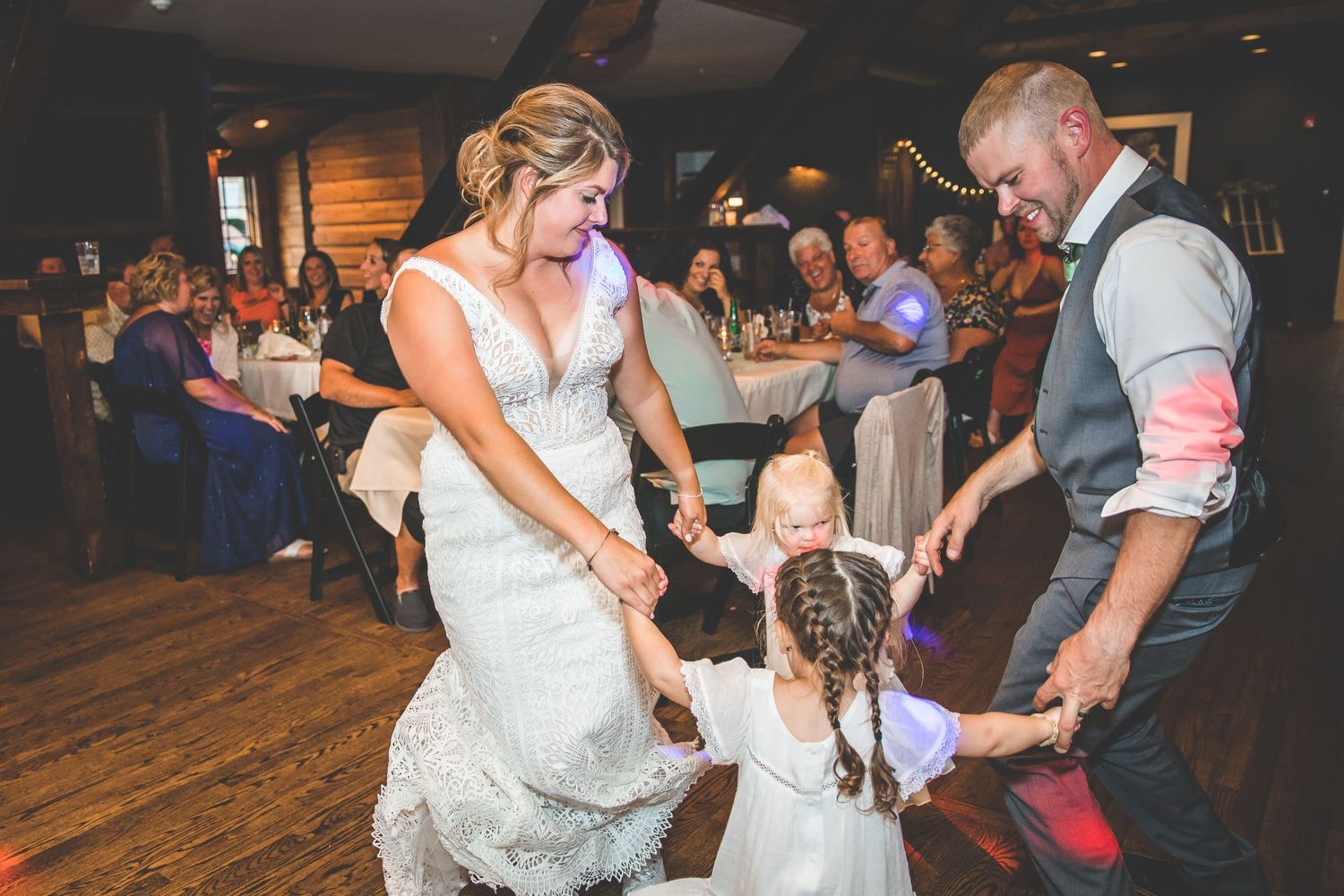 Lively wedding reception with guests dancing and celebrating under warm lighting.