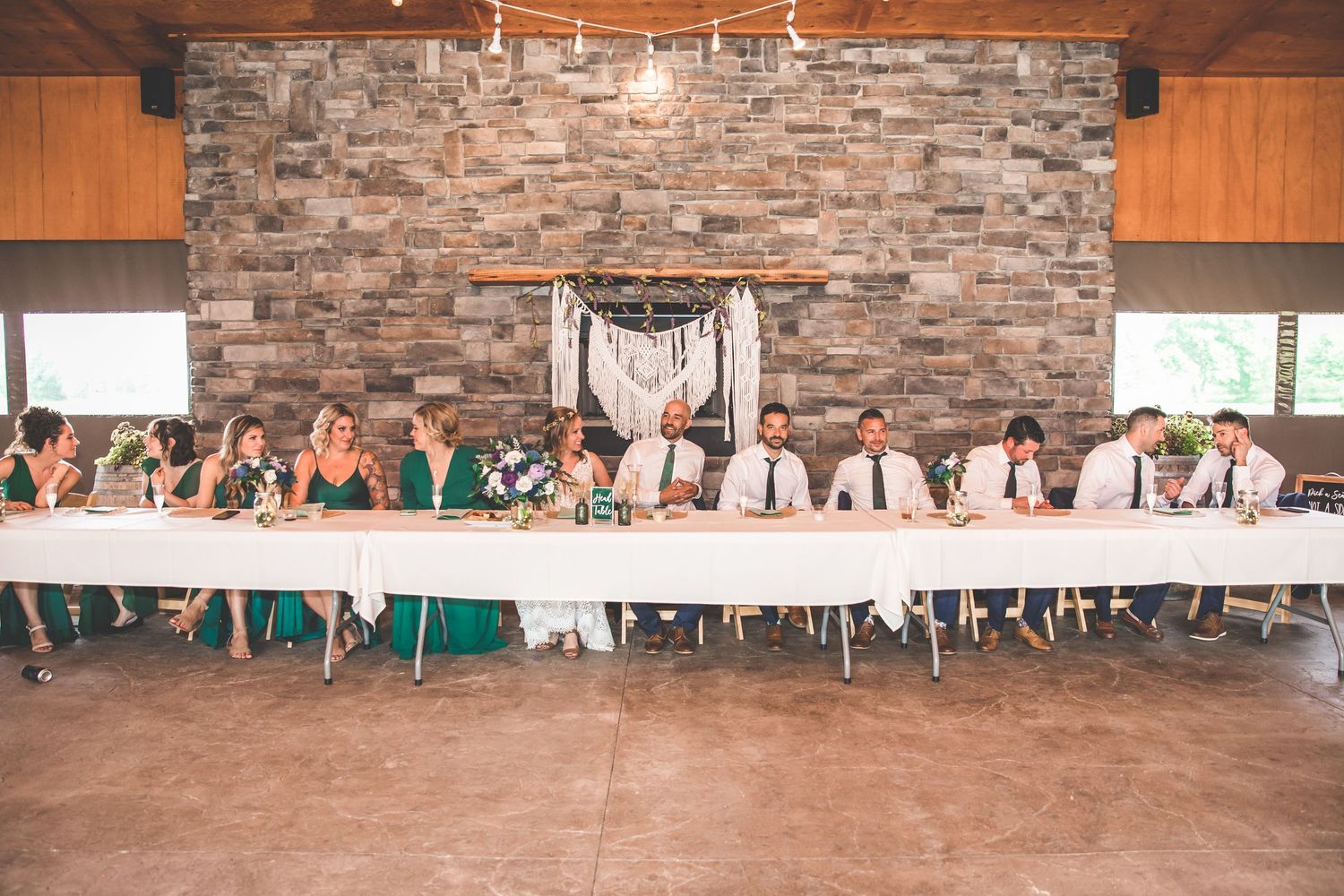 Wedding reception venue with stone walls, wooden beams, and elegant table settings.