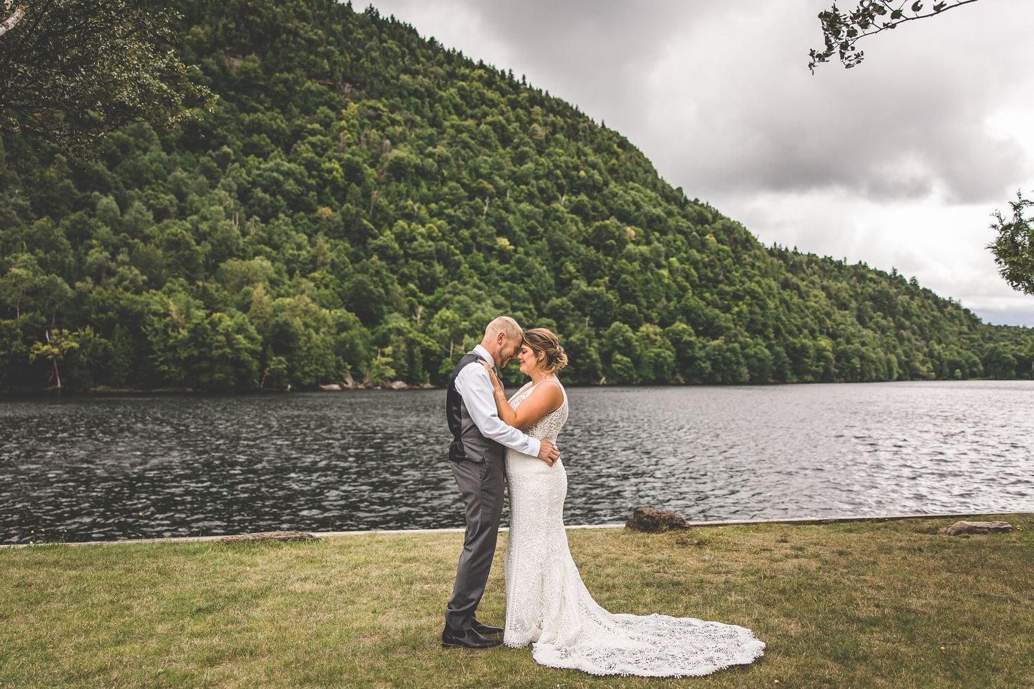 A romantic wedding moment captured against a backdrop of mountains and lake.